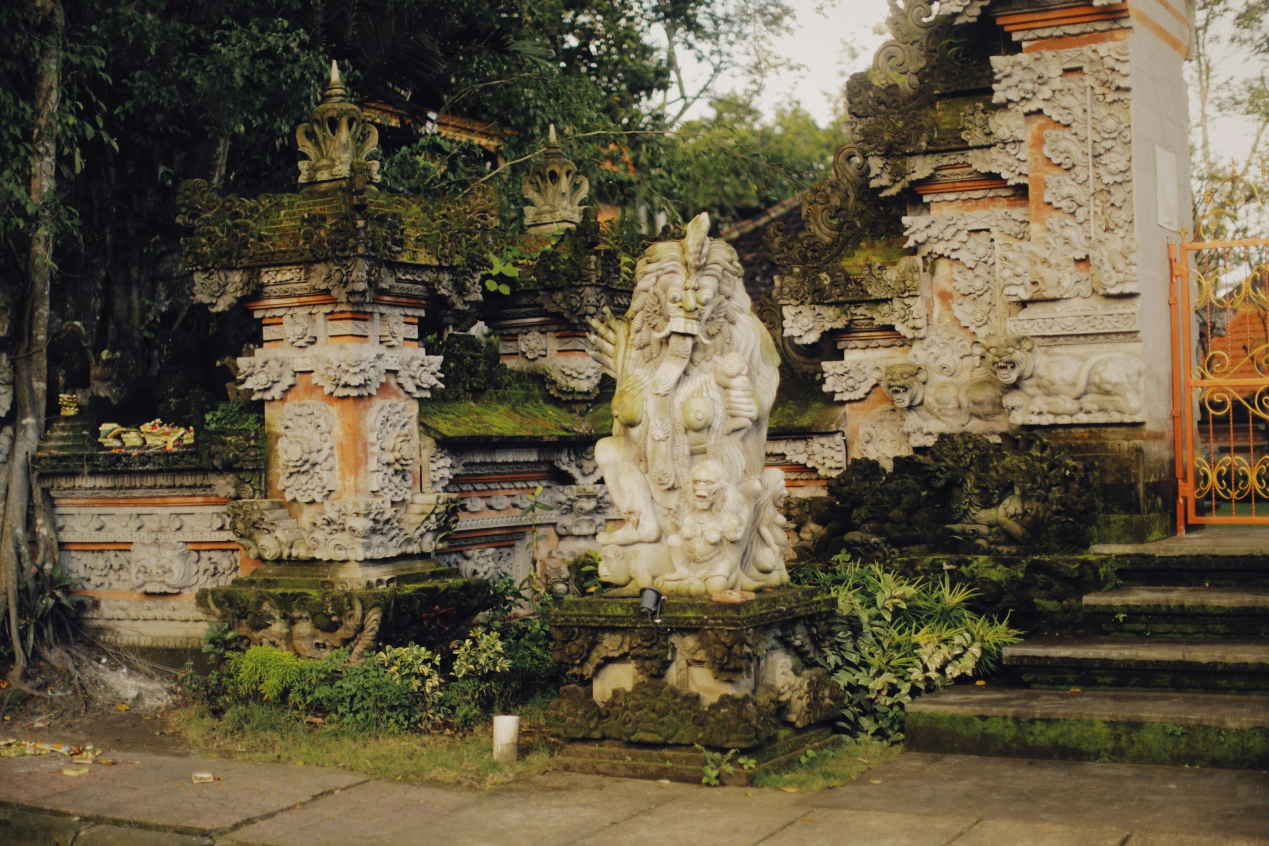 Bali — Intricate stone sculptures and ornate architecture at an ancient temple entrance surrounded by lush greenery.