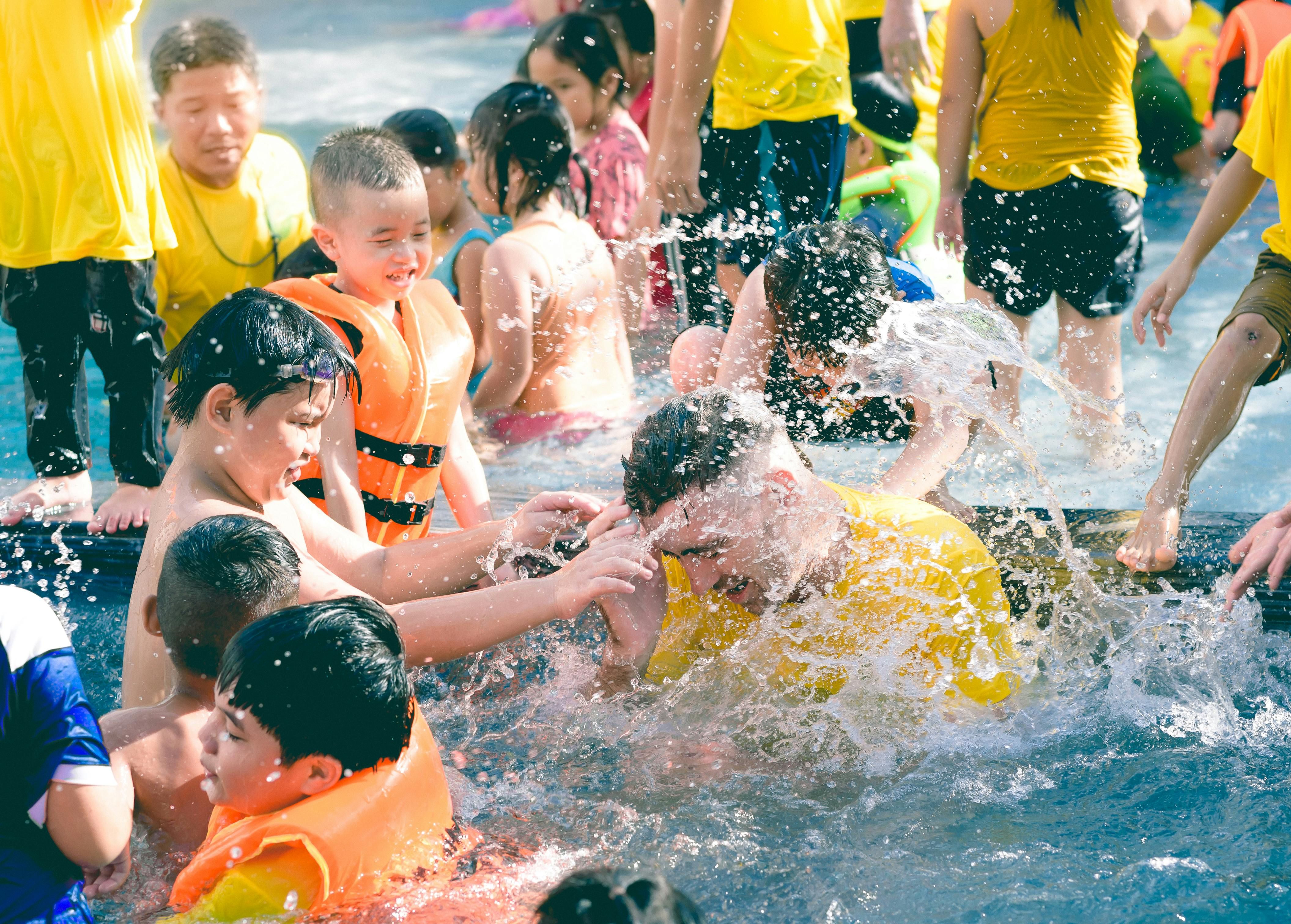 Bali — Joyful scene of children splashing and playing in a brightly lit pool.