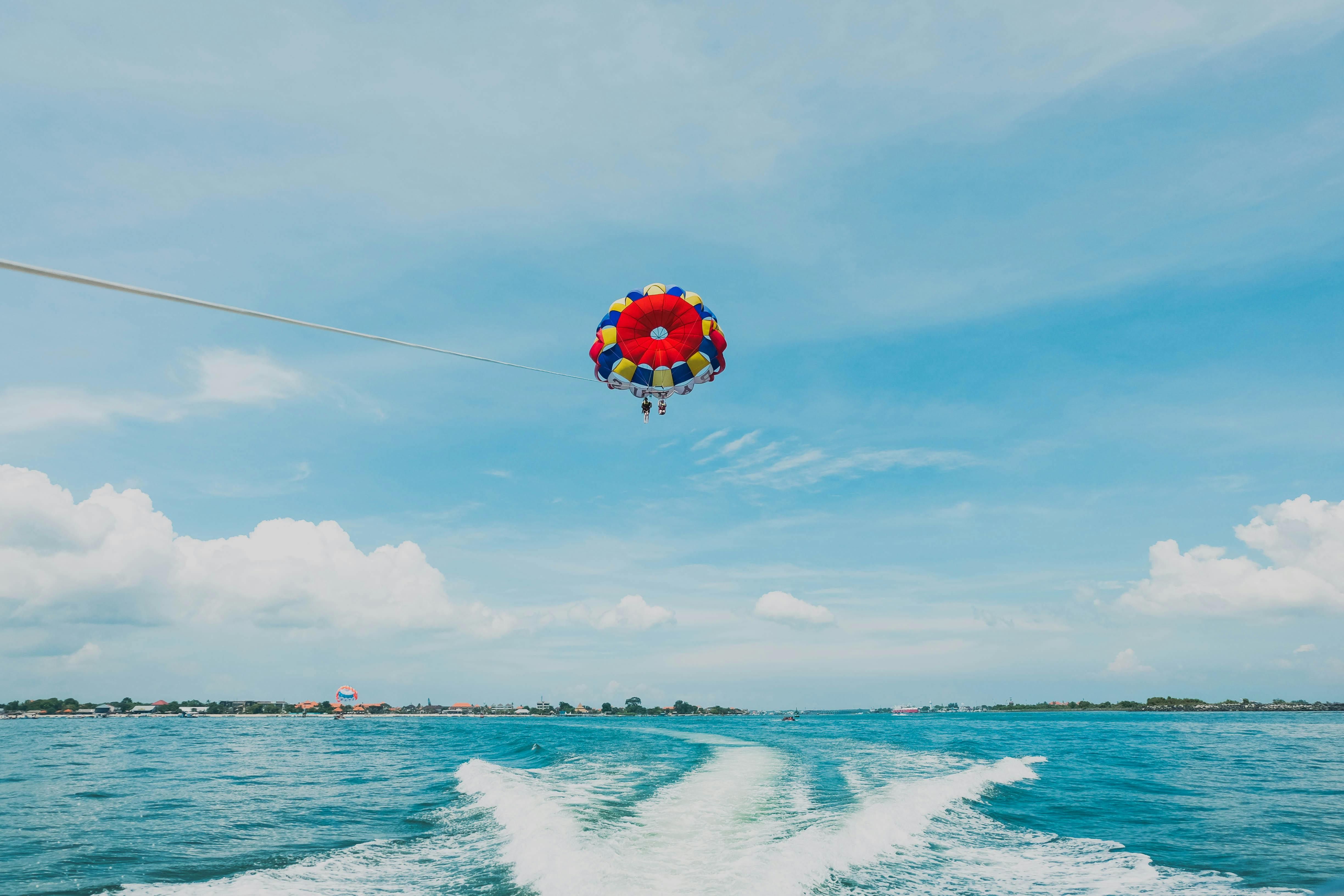 Bali — Thrilling parasailing experience over clear blue ocean waters with vibrant parachute.