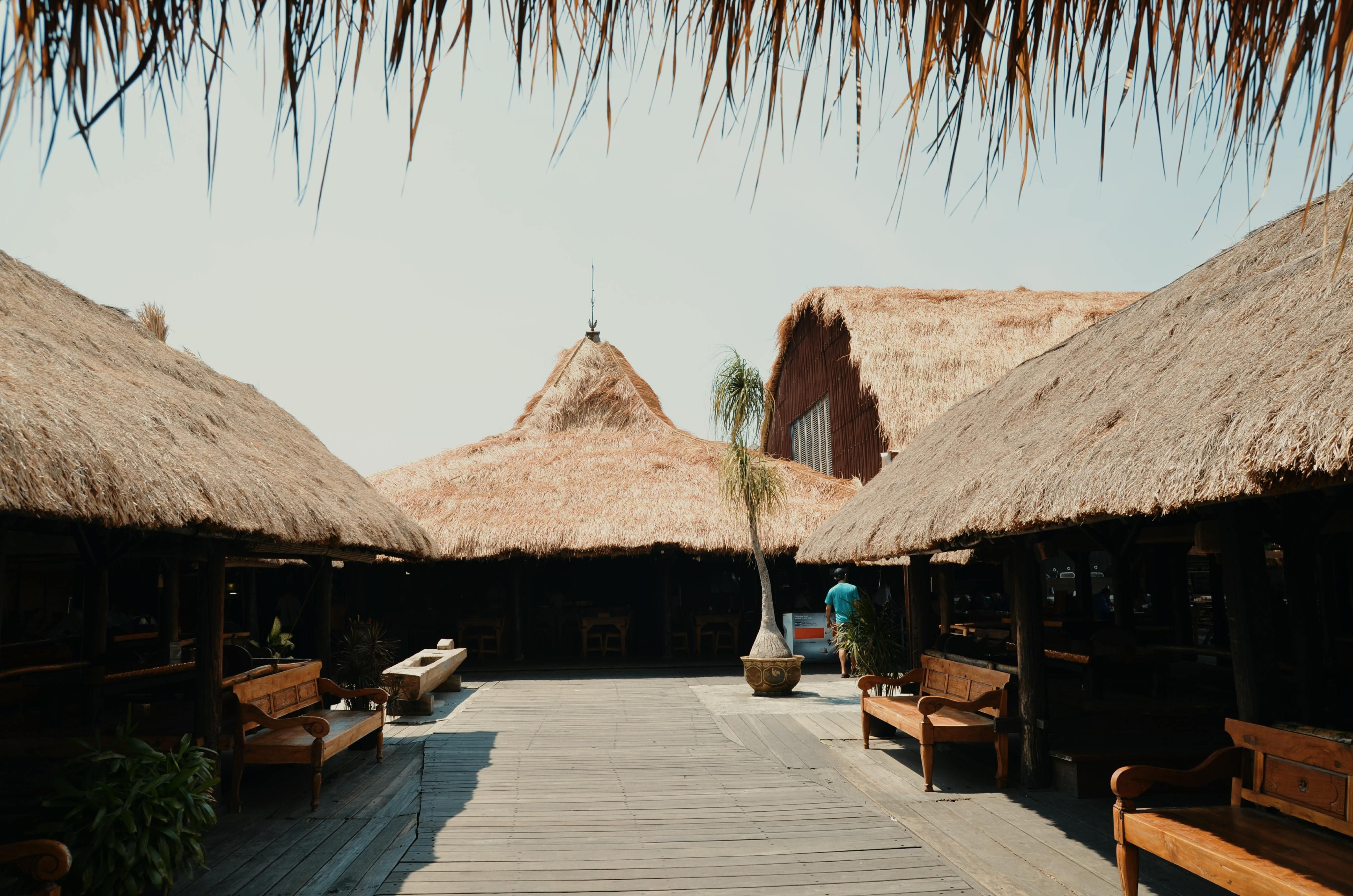 Bali — A relaxing outdoor pavilion with thatched roofs and wooden benches on a sunny day.