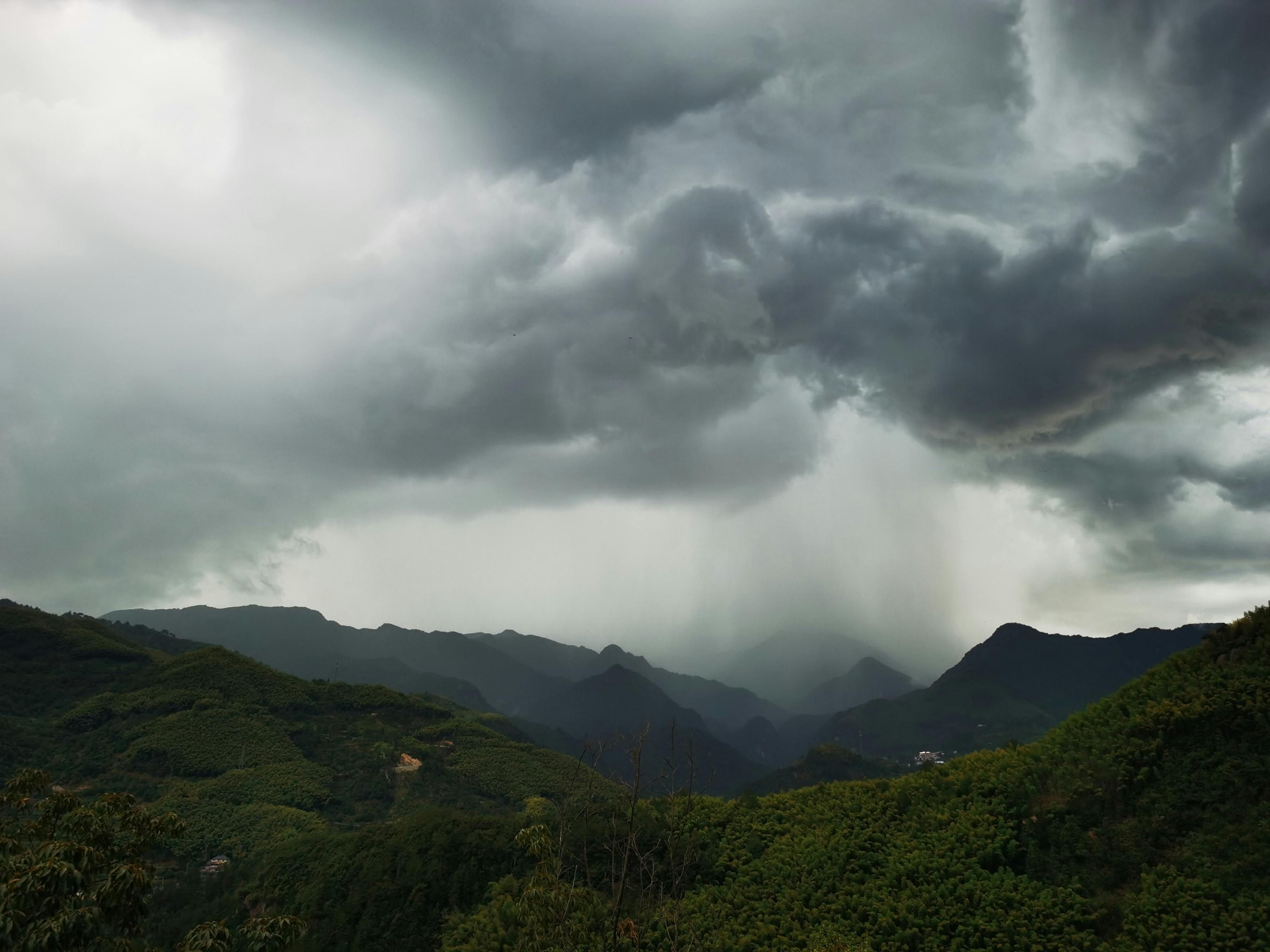 Bali — A breathtaking view of dramatic rain clouds over lush green mountains in Hangzhou, China.