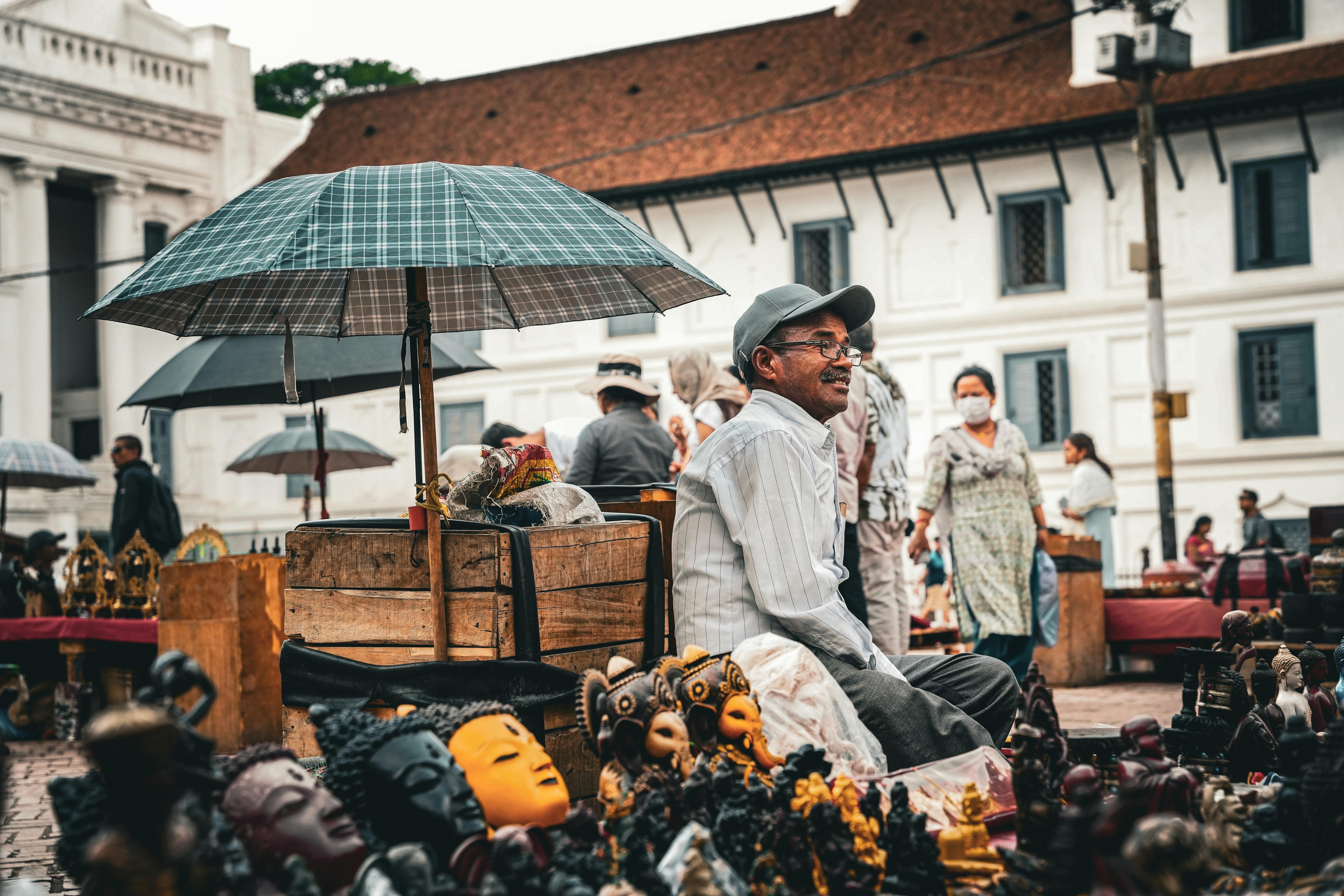 Bali — A street vendor selling sculptures in a bustling outdoor market area, covered by umbrellas.