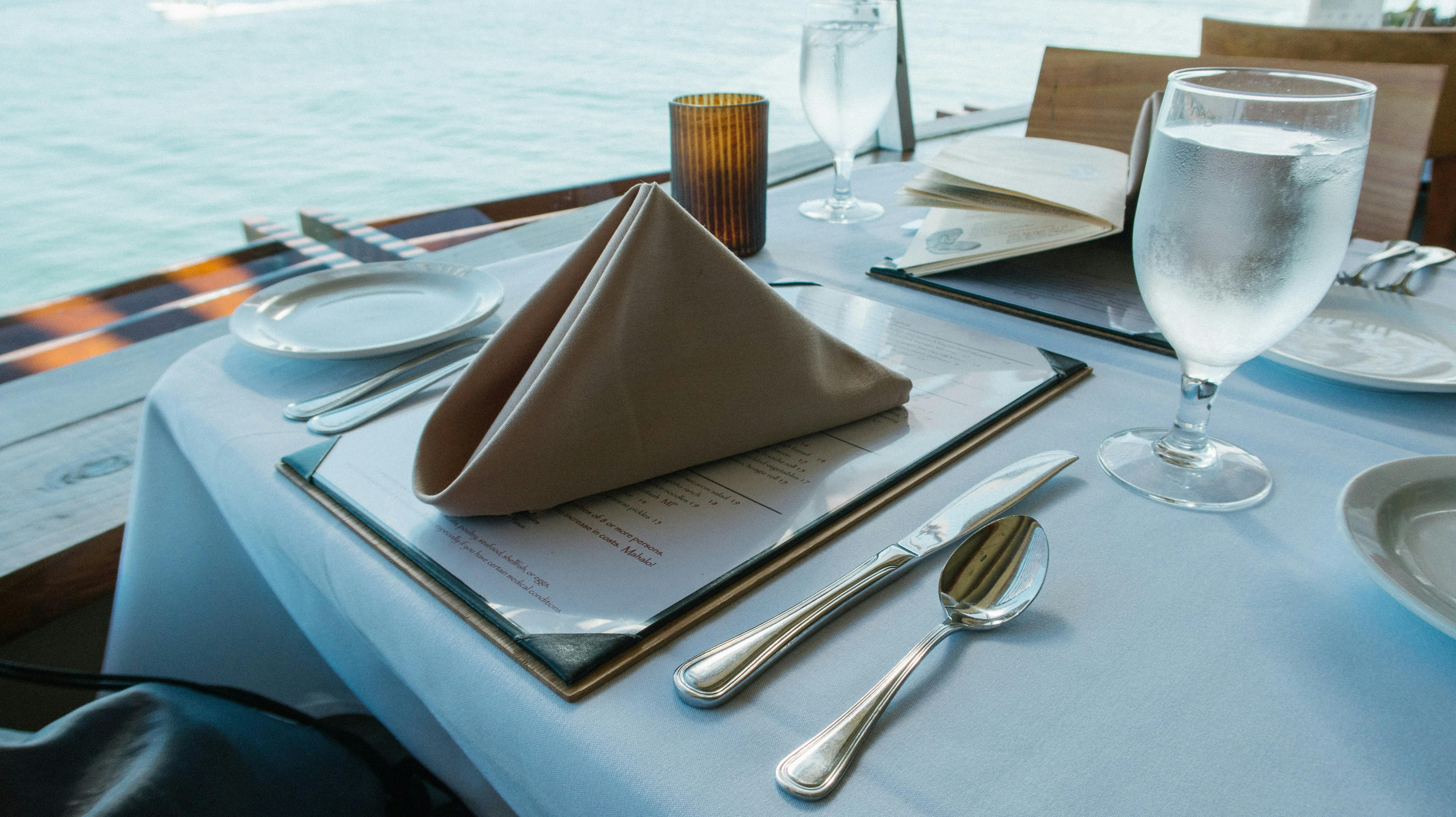 Bali — Luxurious dining table setup by the sea with elegant tableware and glassware.
