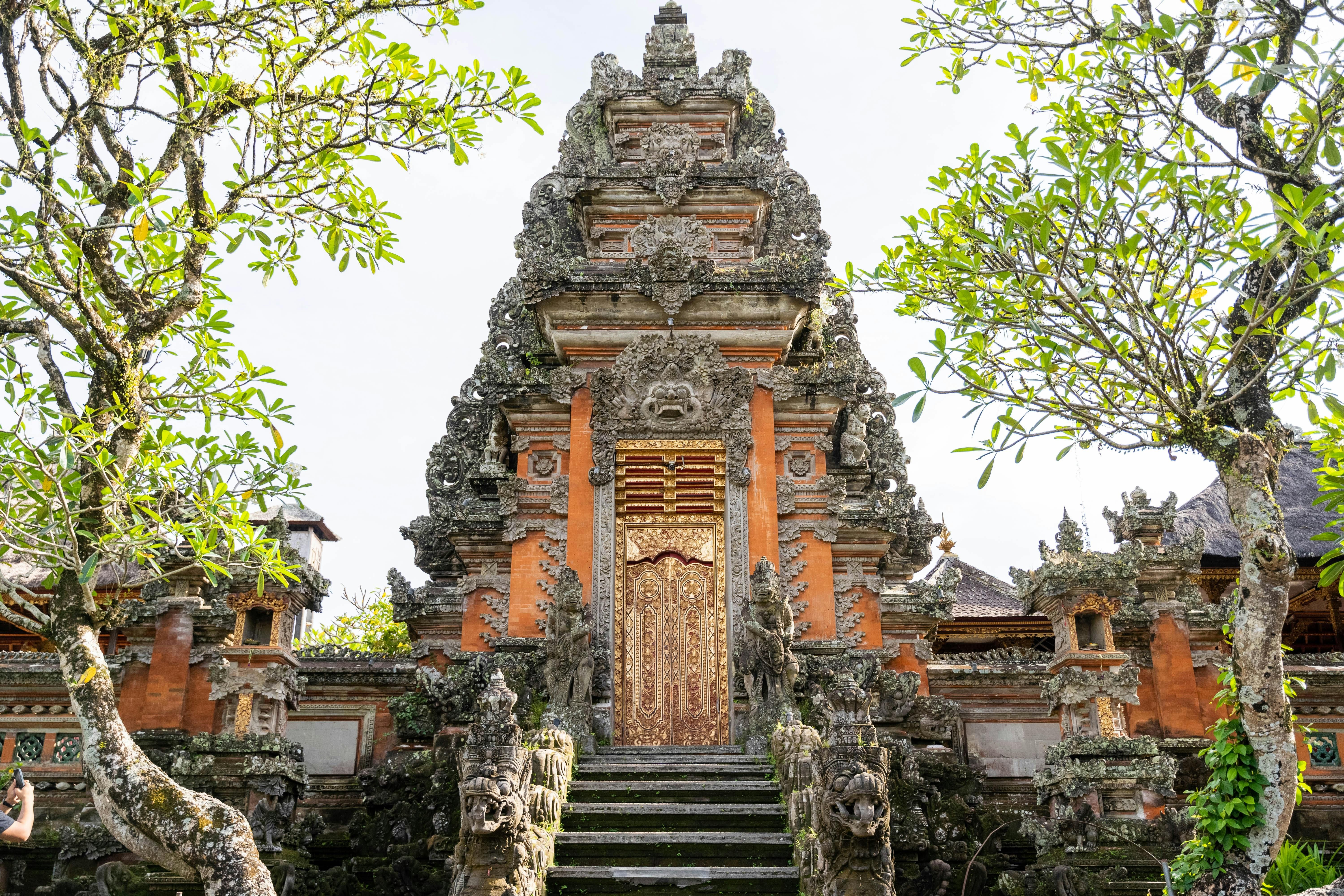 Bali — A detailed stone entrance of a traditional Balinese temple surrounded by lush greenery in Ubud.