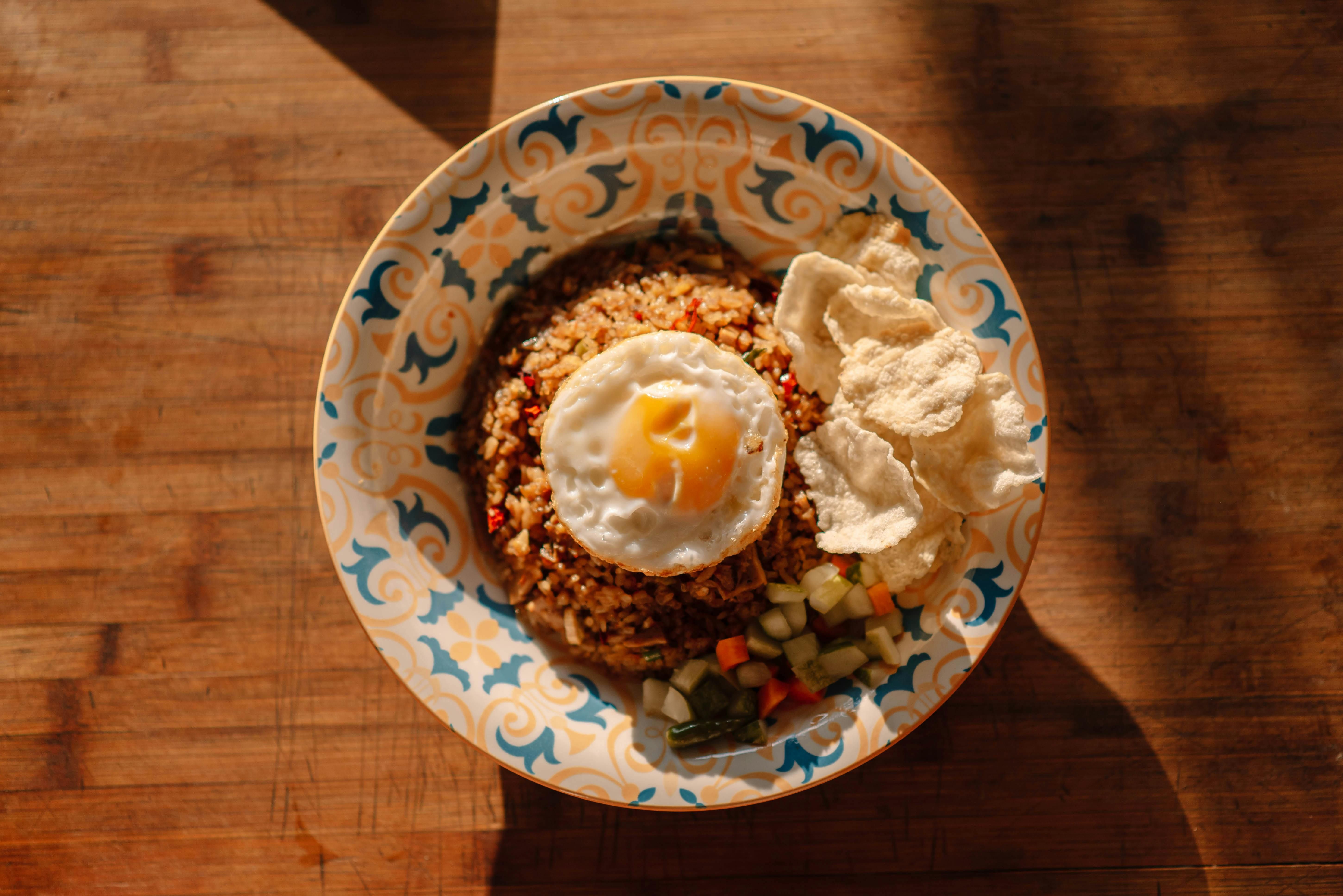 Bali — Top view of nasi goreng with fried egg, krupuk, and vegetables on a decorative plate.