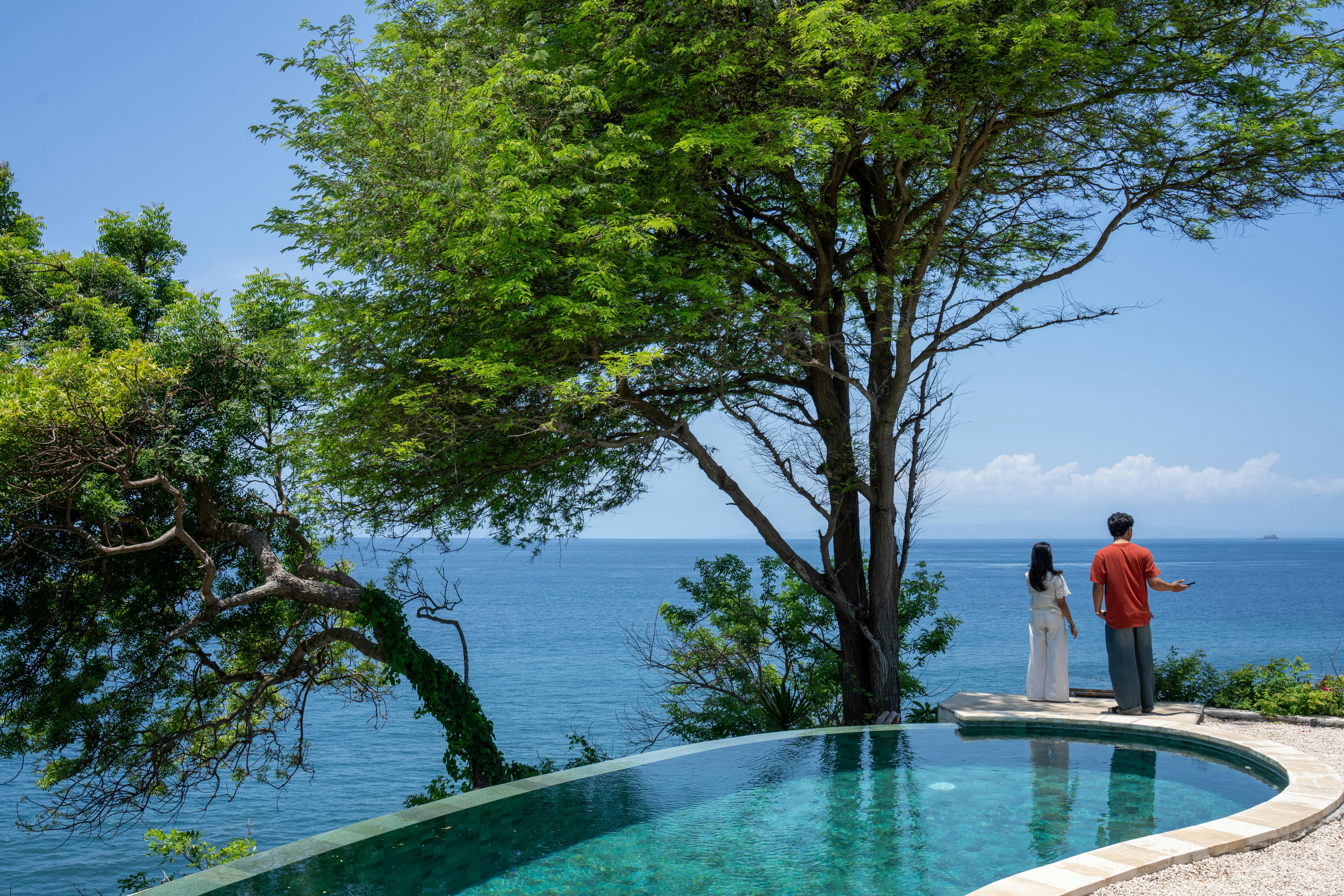 Bali — Couple enjoys the scenic ocean view from a luxurious infinity pool in Bali, Indonesia.