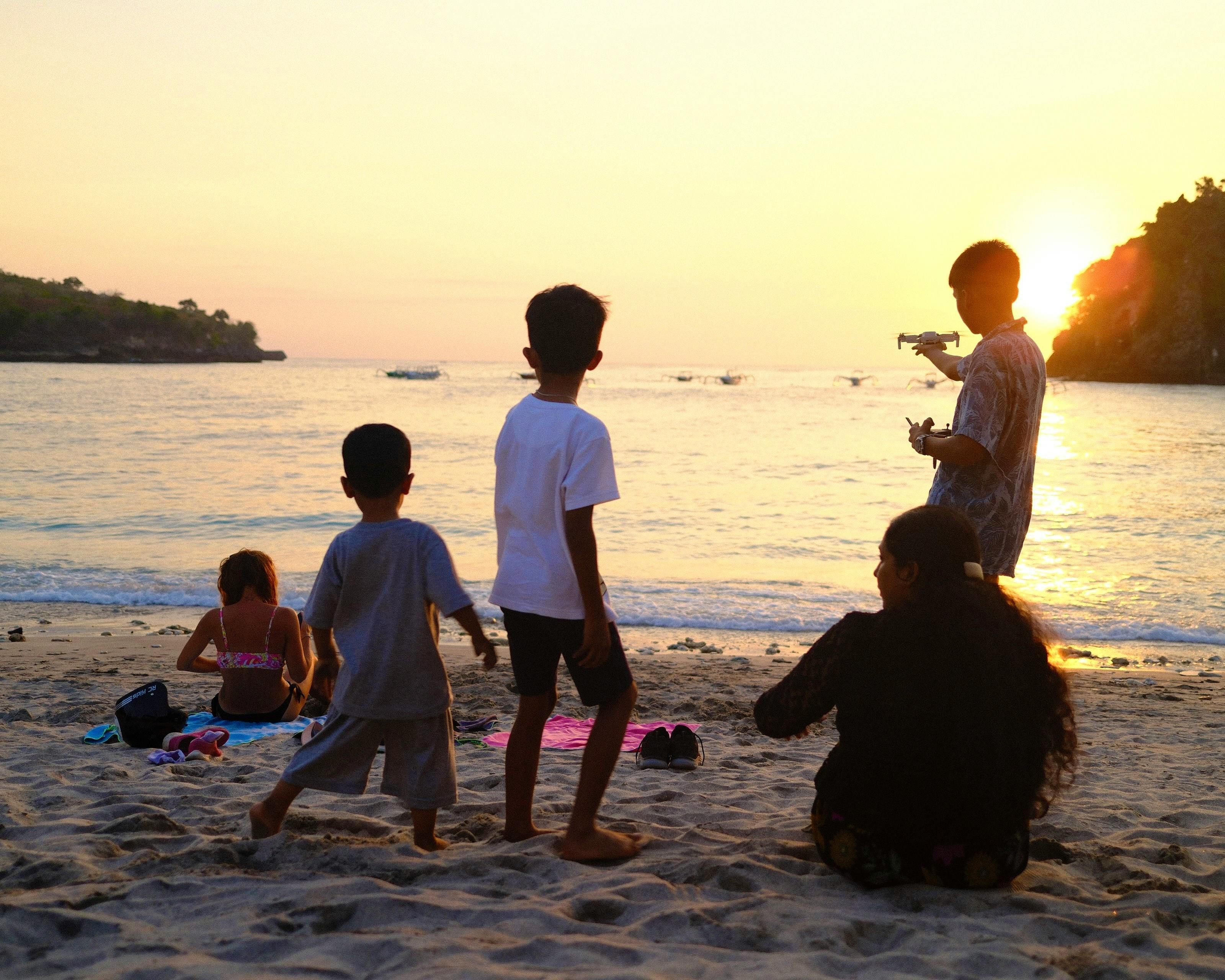 Bali — A family enjoys a beautiful sunset on a Bali beach with children playing and adults relaxing.