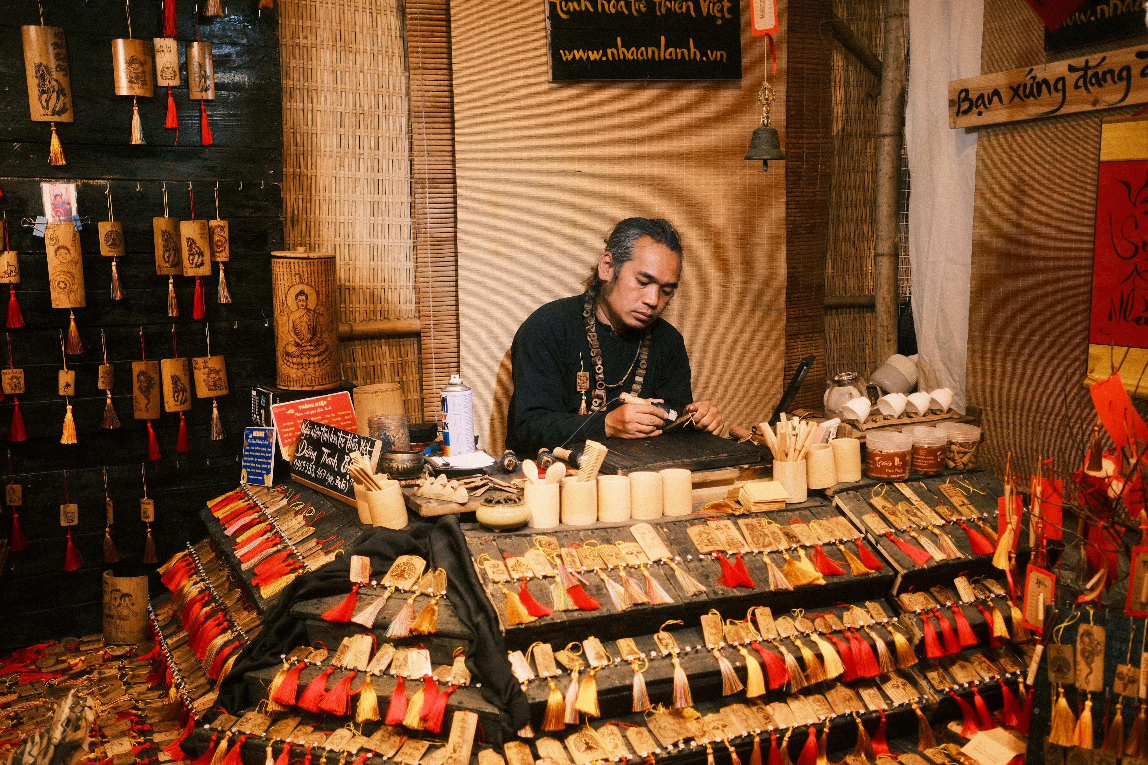 Bali — Skilled artisan creating intricate wooden decorations at a vibrant market stall.