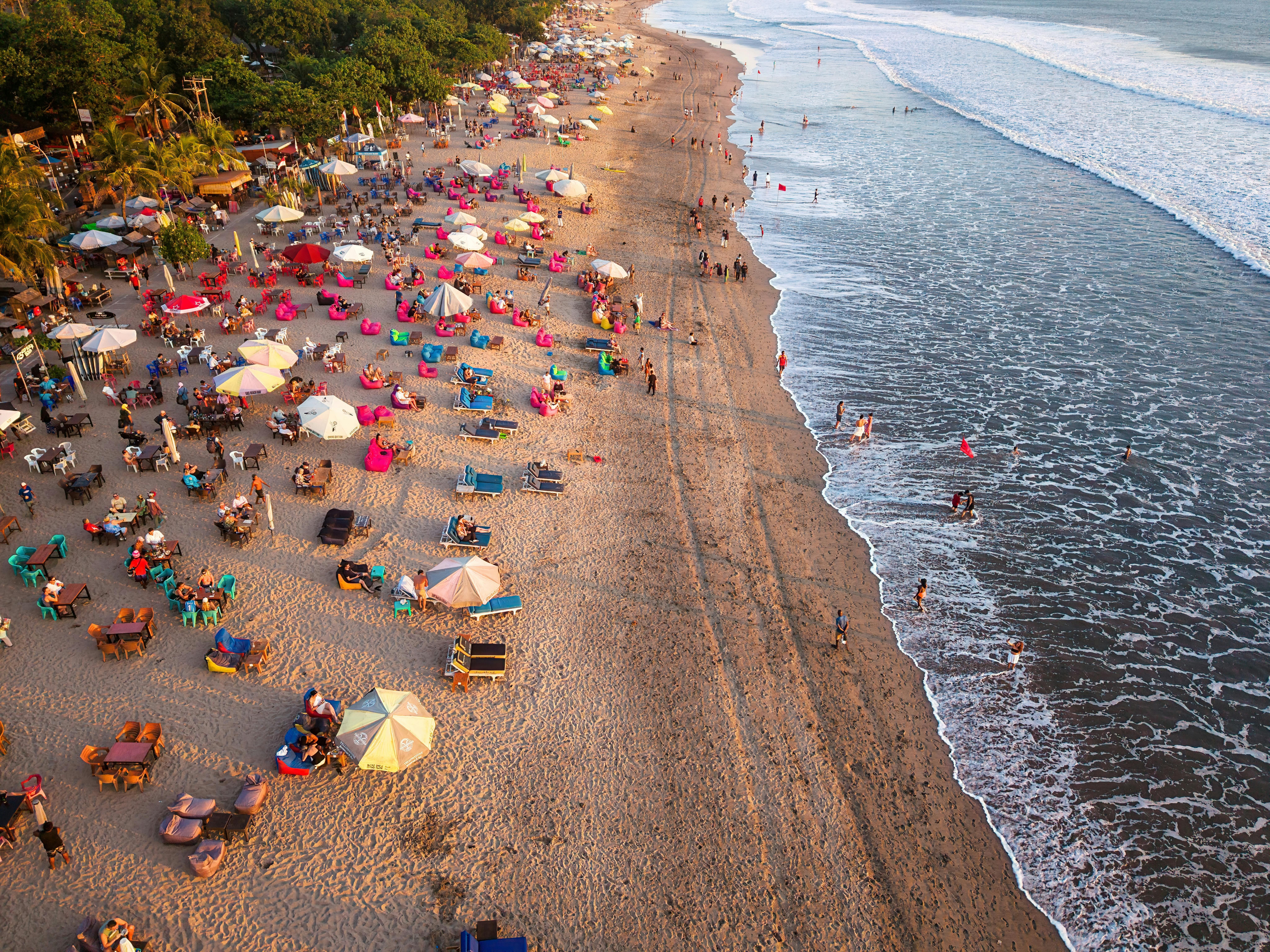 Bali — A lively beach scene in Bali, Indonesia, captured from above during sunset.
