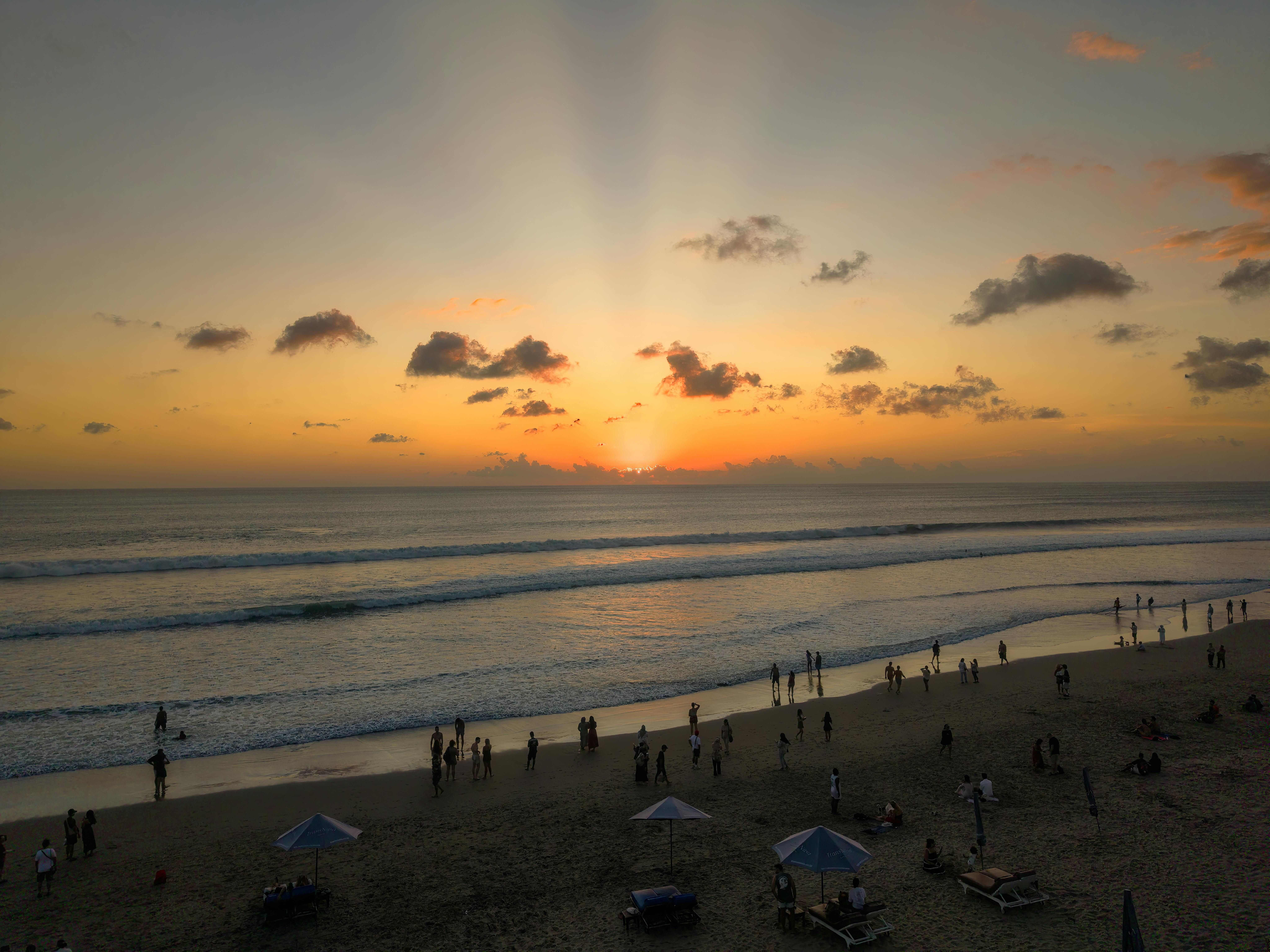Bali — Stunning sunset on a Bali beach with vibrant colors and silhouettes of people.