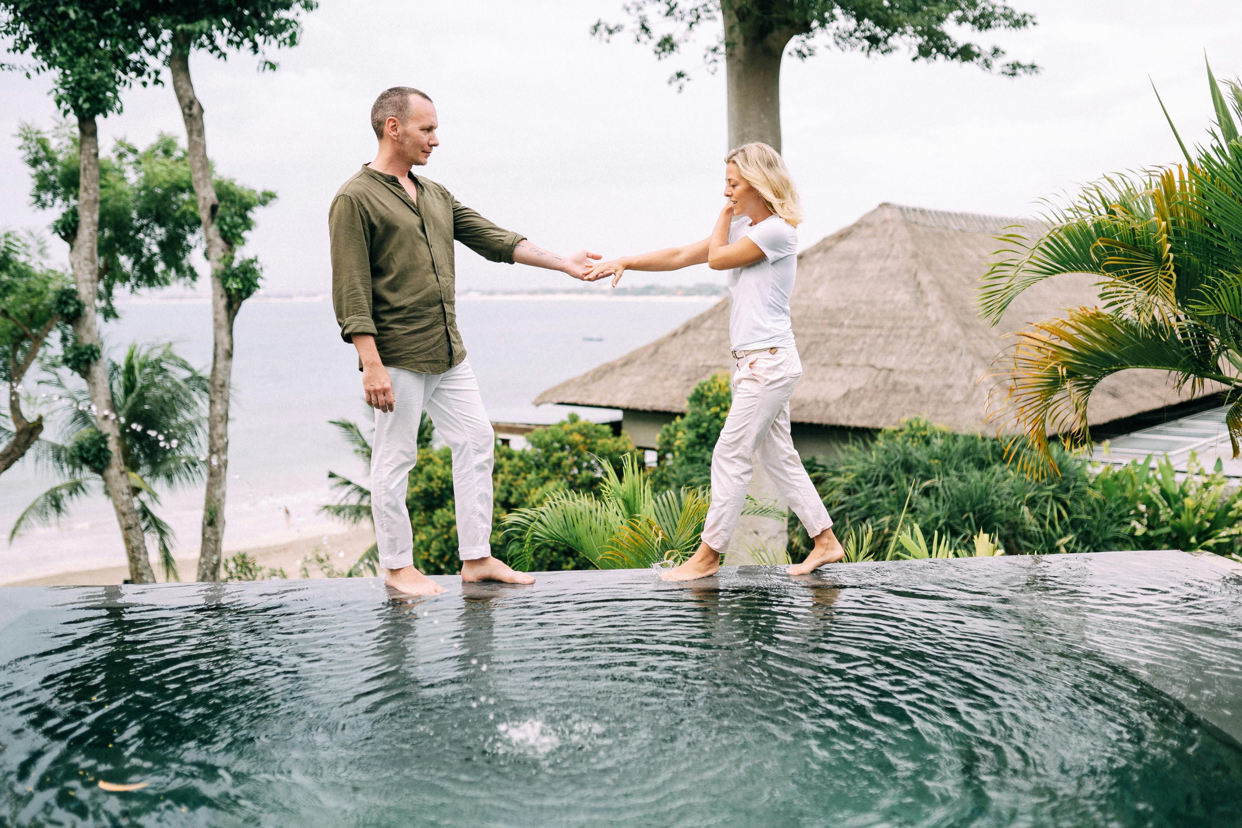 Bali — Couple holding hands and enjoying a tropical vacation by the poolside.