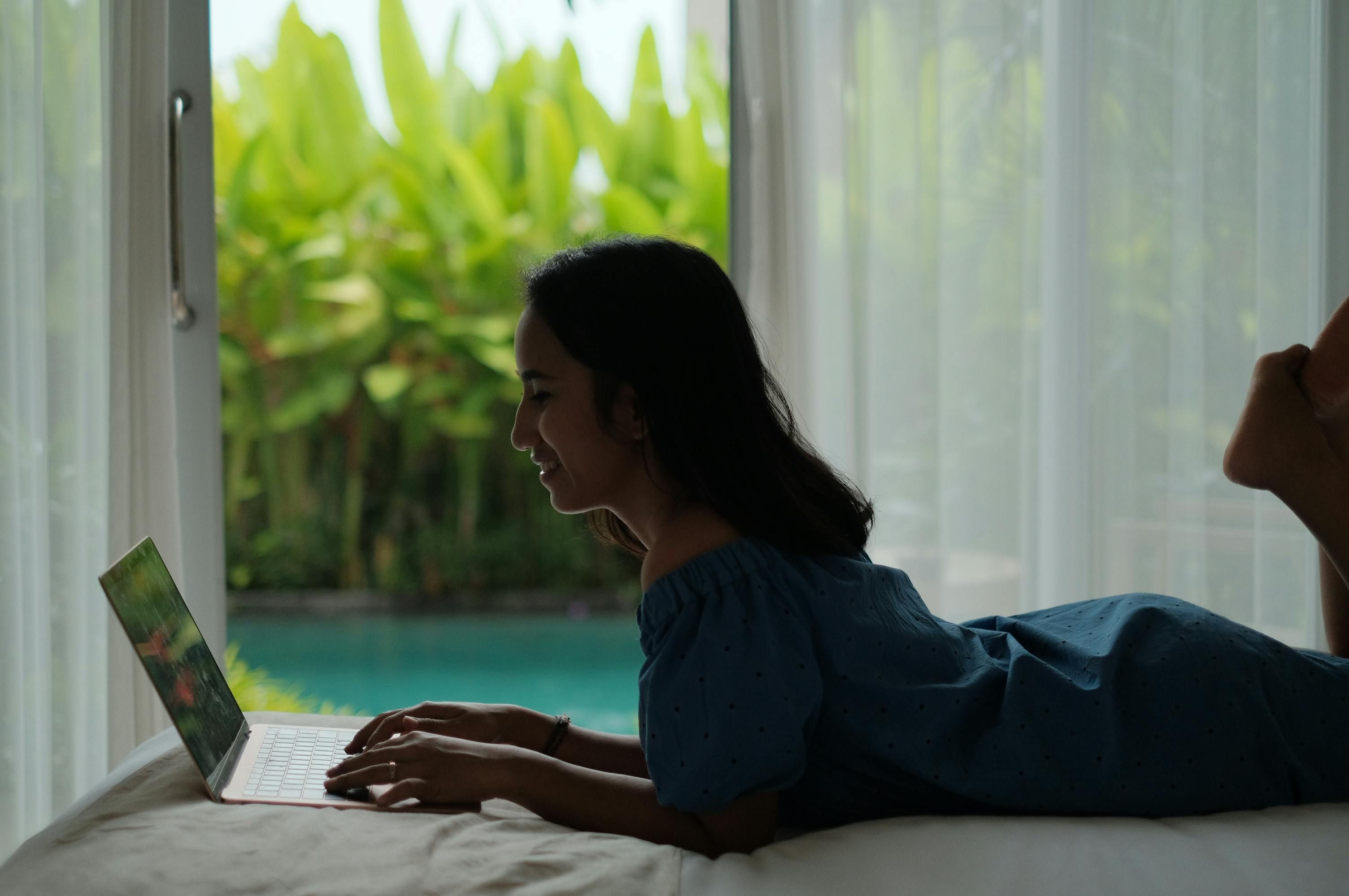 Bali — Asian woman working on a laptop indoors in Bali, enjoying a relaxed digital nomad lifestyle.