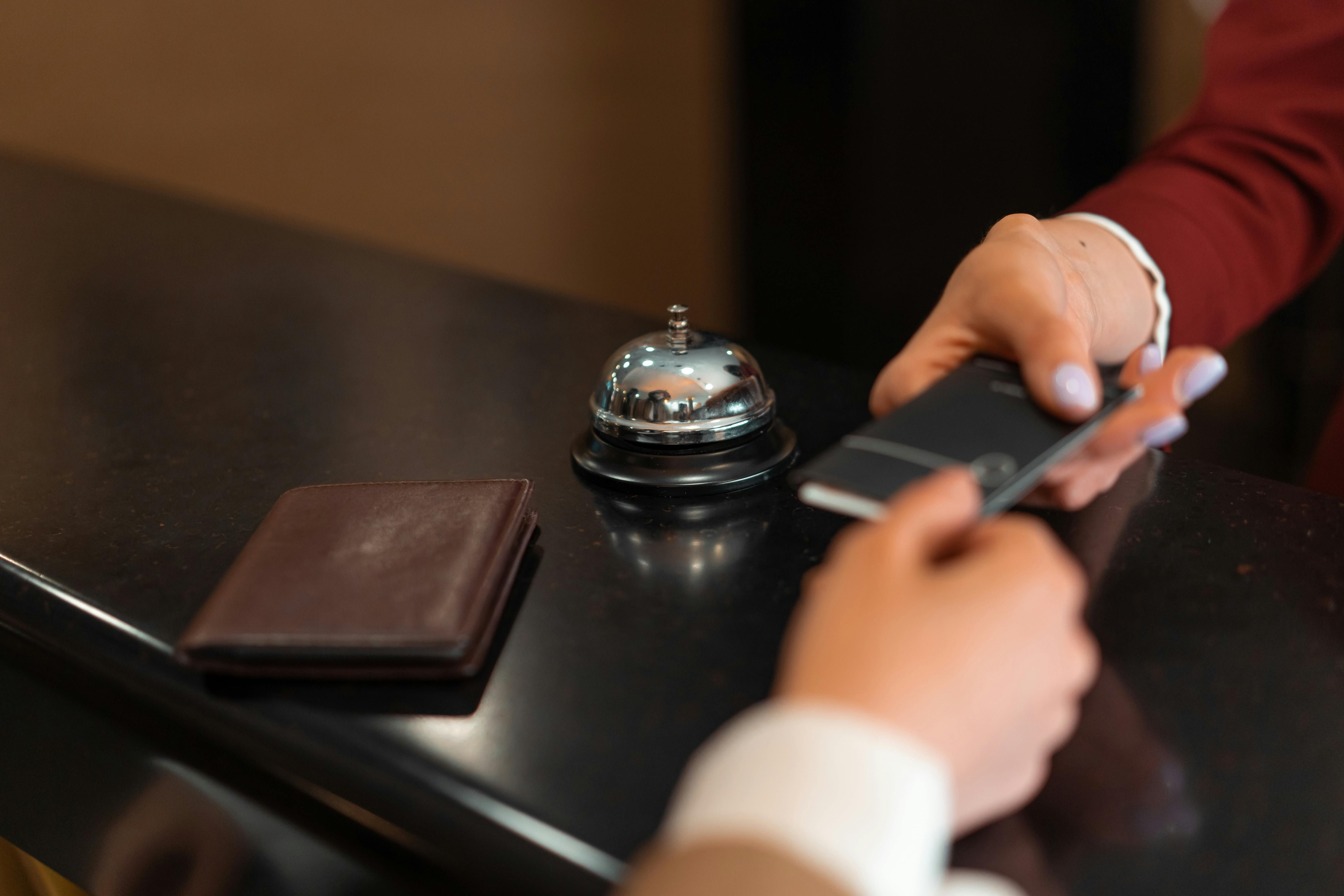 Bali — A close-up of a hotel check-in process with a smartphone and card transaction at the reception desk.