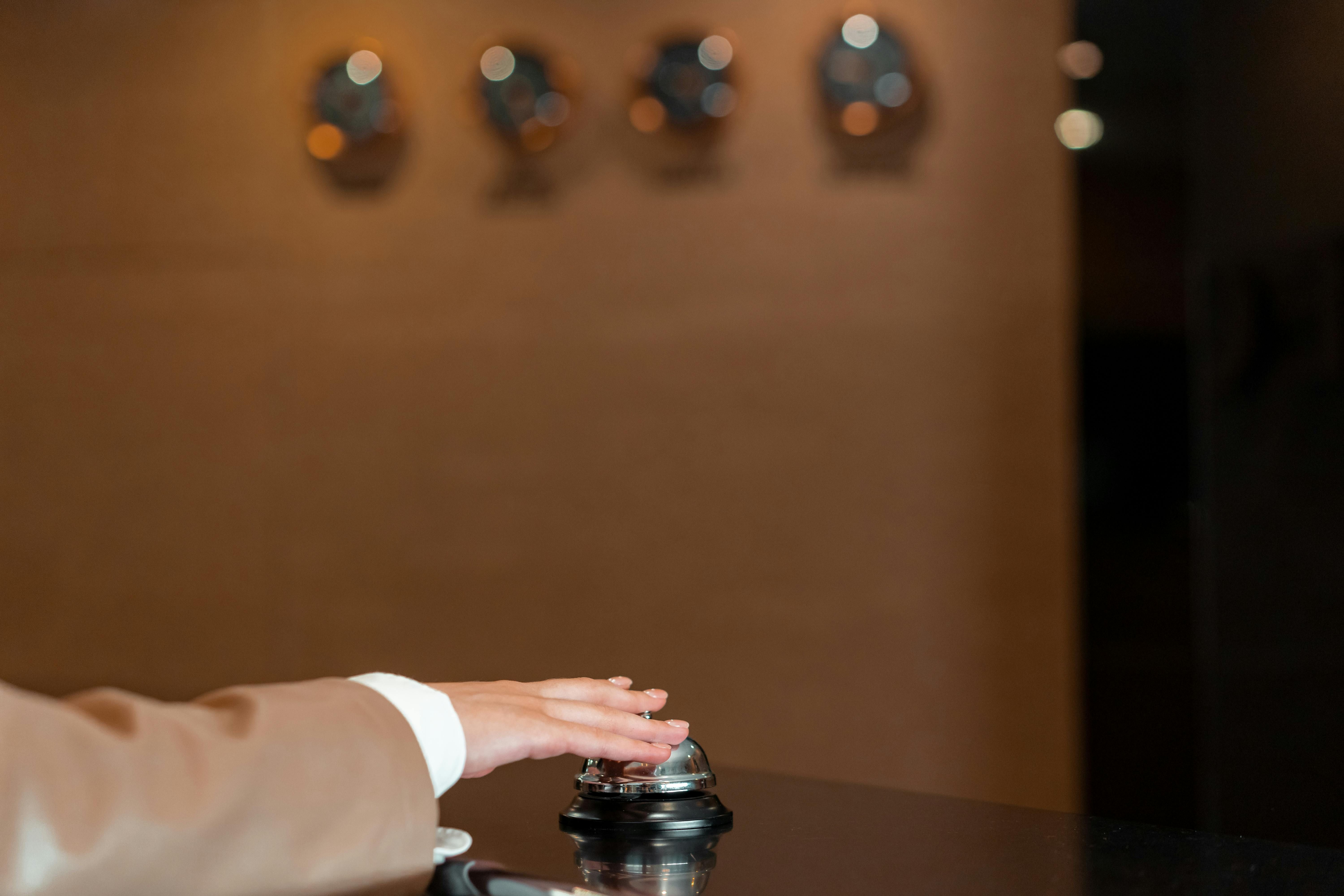 Bali - Sanur — A hand pressing a bell at a hotel reception, symbolizing service and hospitality.