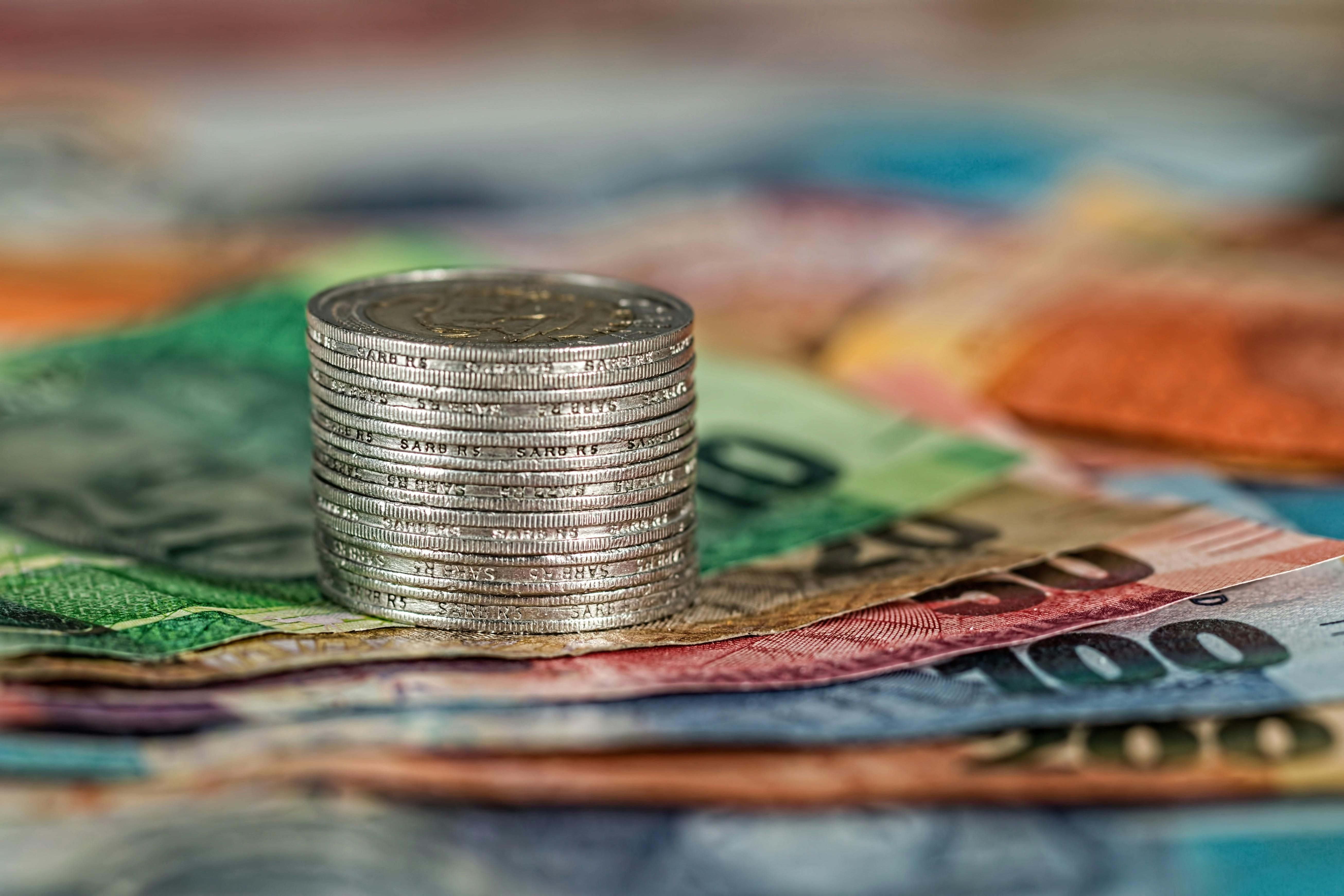 Fiji — A stack of coins on top of various colored banknotes, symbolizing finance and currency.