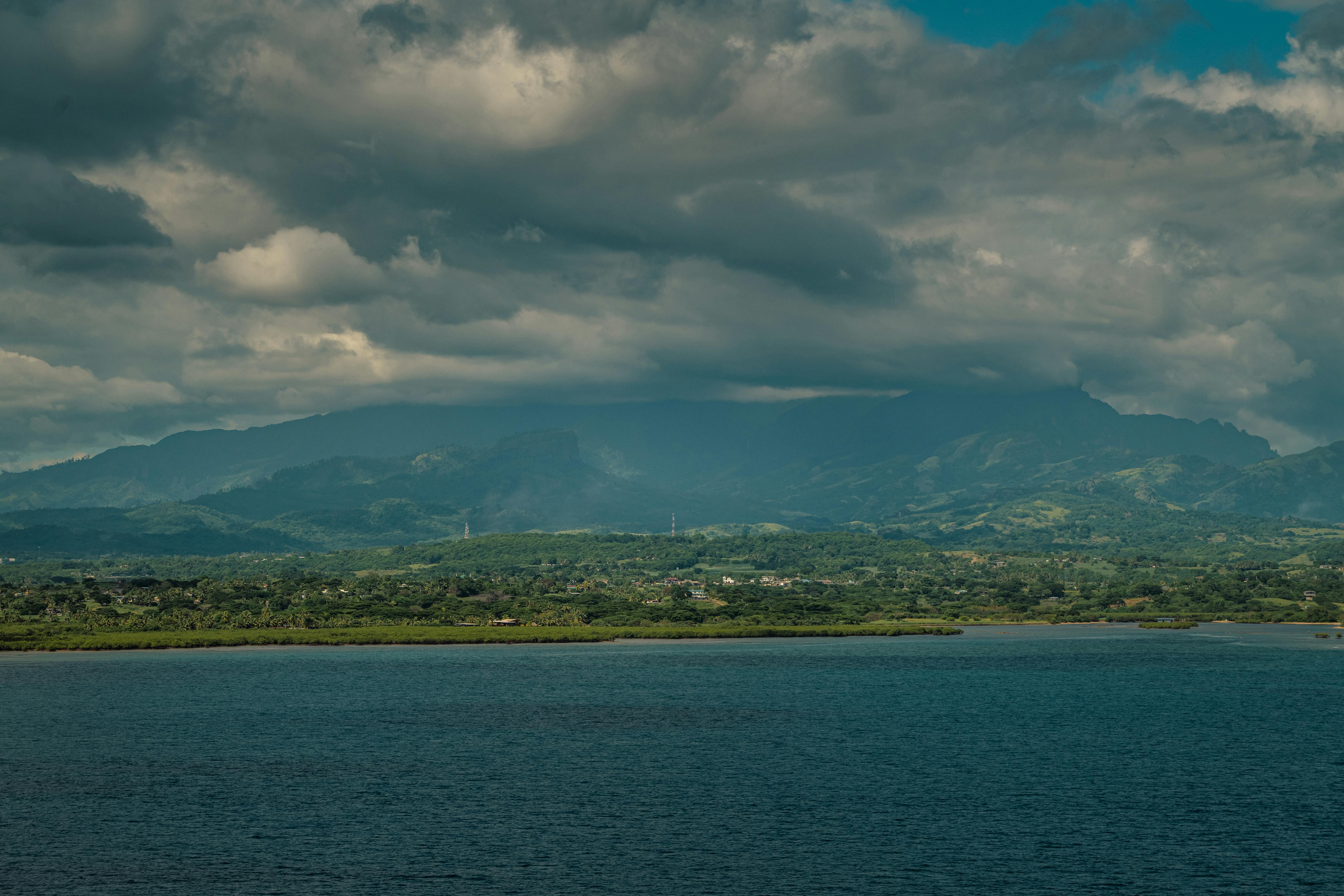 Fiji — Explore the stunning landscape of Suva with lush mountains and the Pacific Ocean under a cloudy sky.