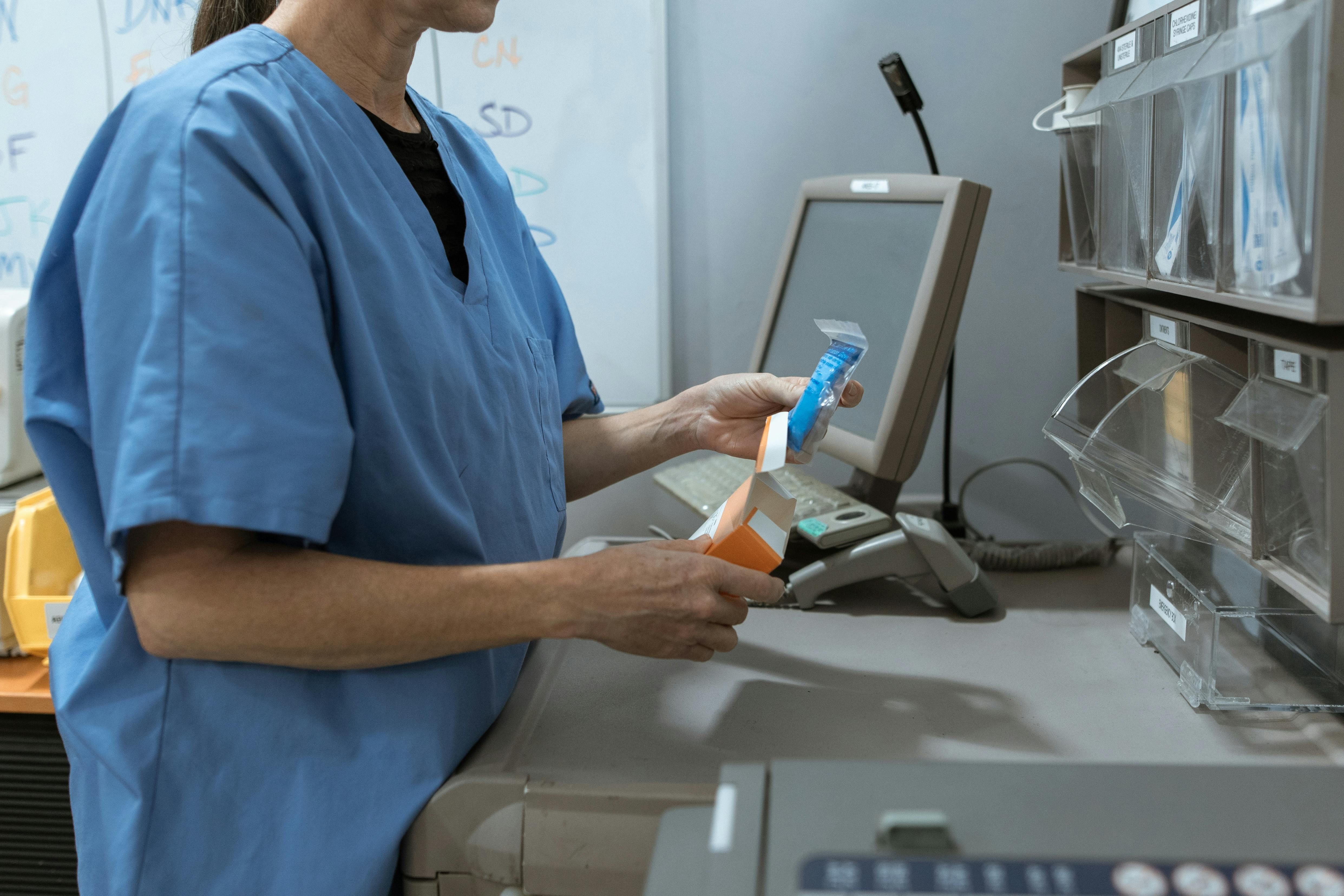 Fiji — Healthcare worker in scrubs organizing medication in a medical facility.