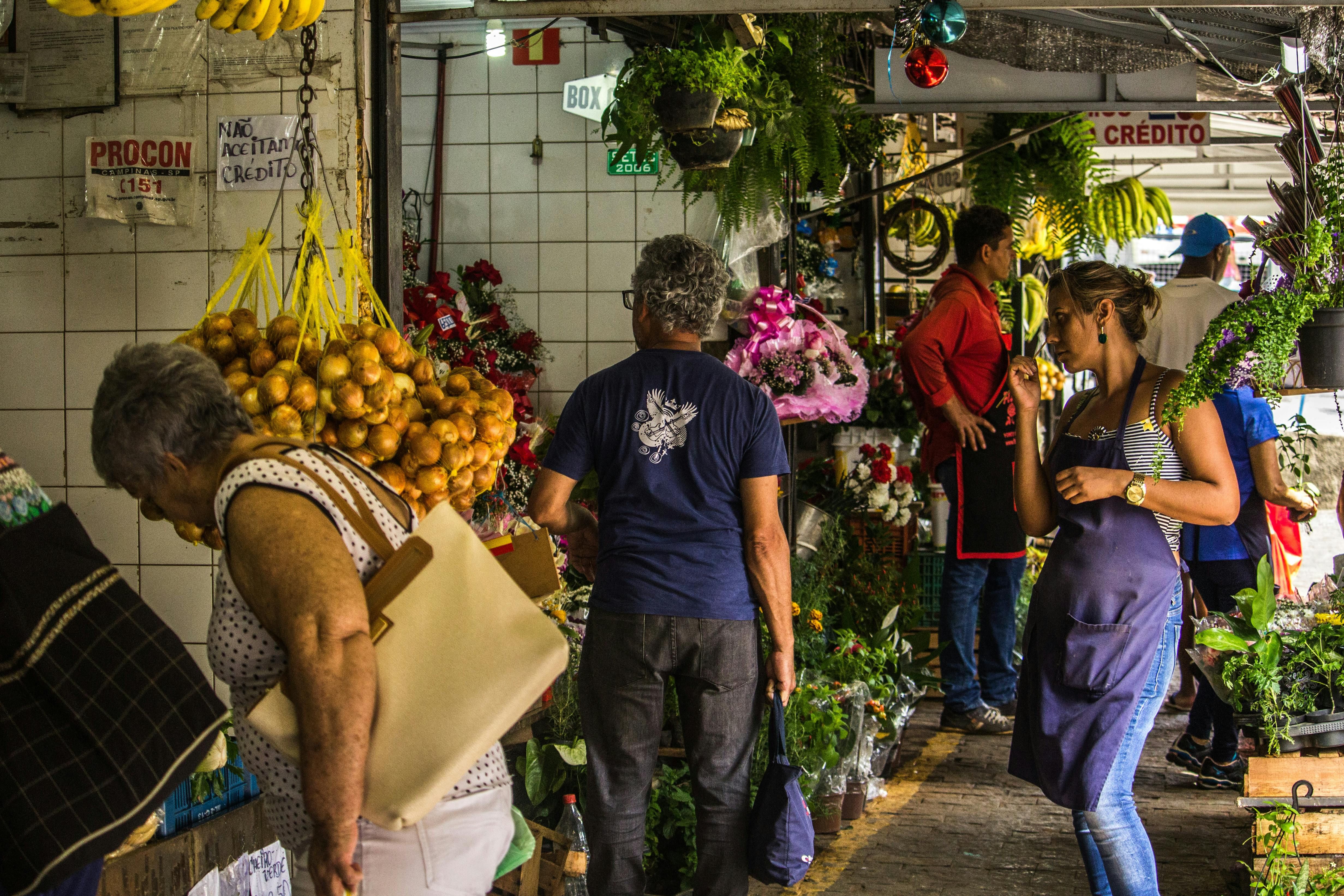 Fiji — Vibrant indoor marketplace scene with diverse shoppers among colorful flower and fruit stalls.