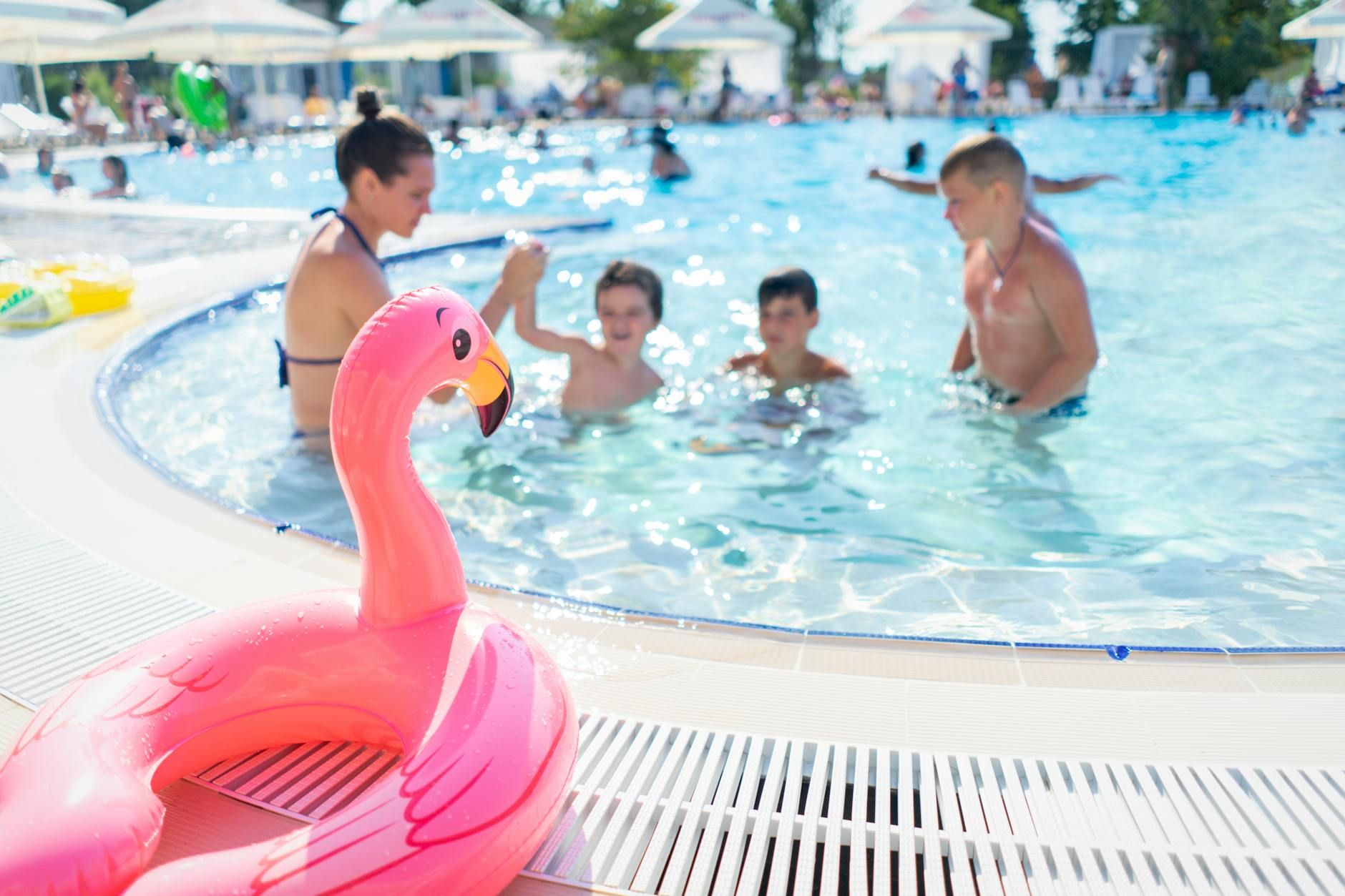 Western family playing in resort pool with pink flamingo float — family-friendly water activities