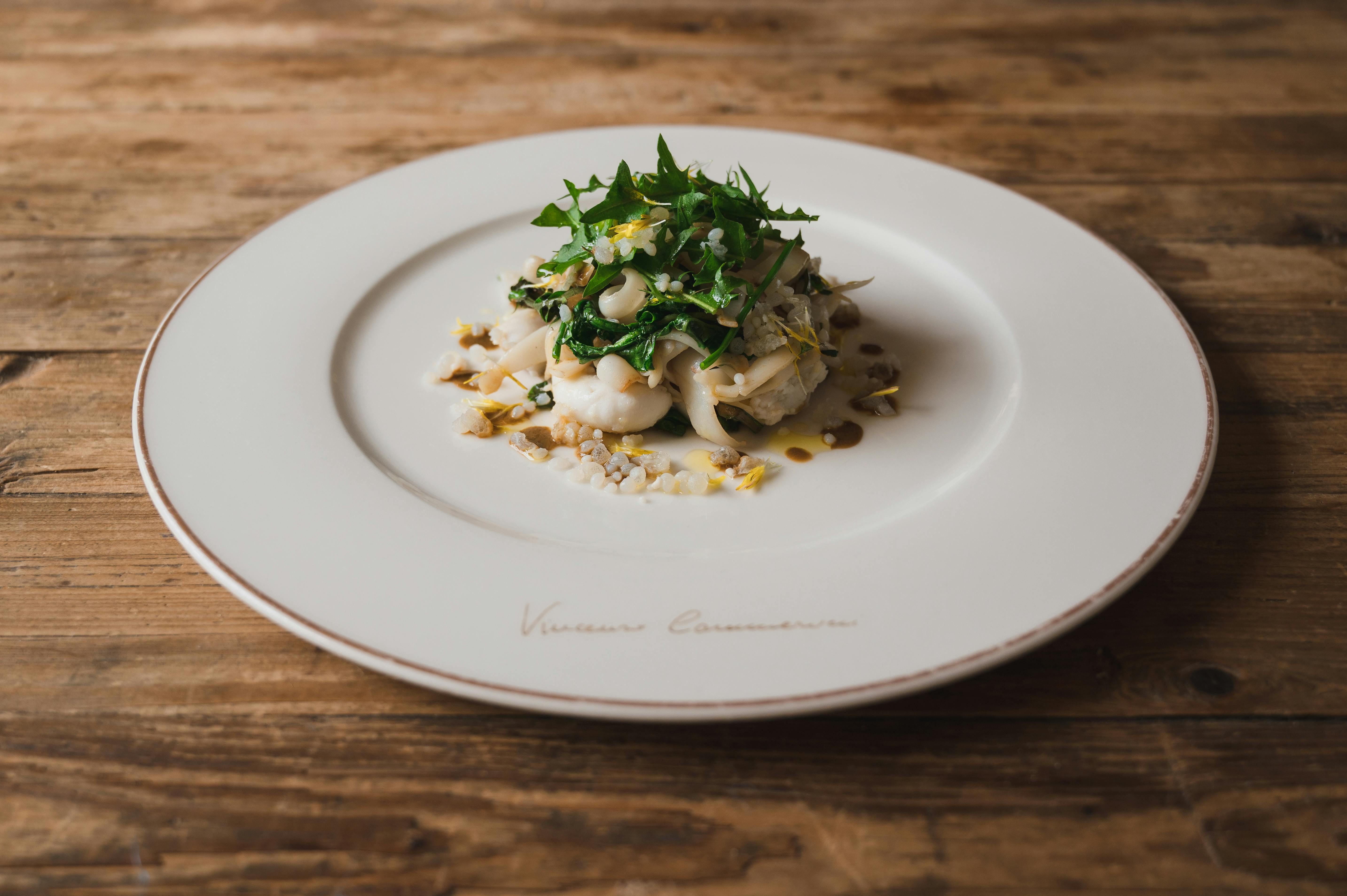 Italy — Elegant gourmet seafood dish with fresh greens served on a rustic wooden table.