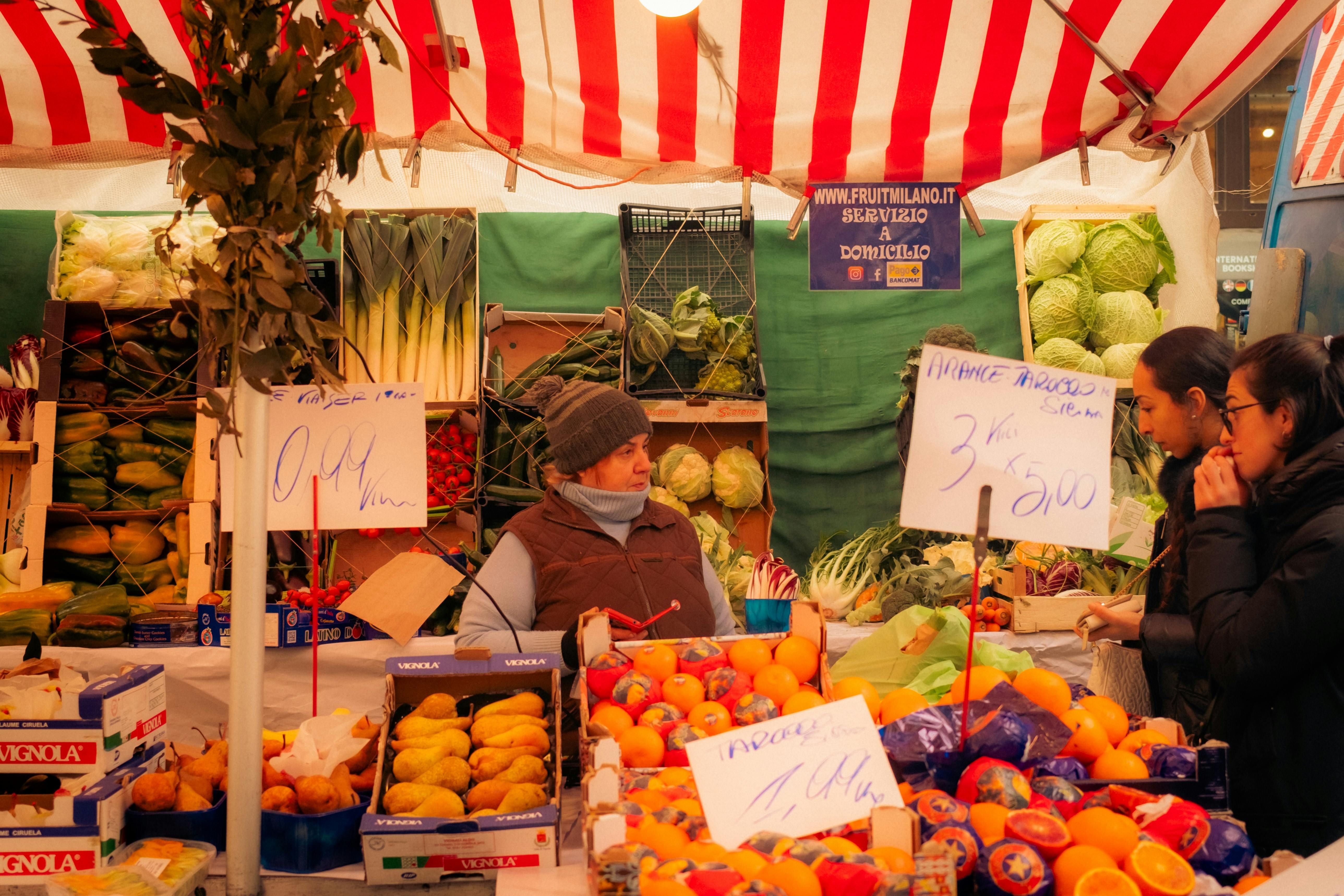Italy — Explore fresh produce at a lively farmers market stall in Milan, showcasing a colorful array of fruits and vegetables.