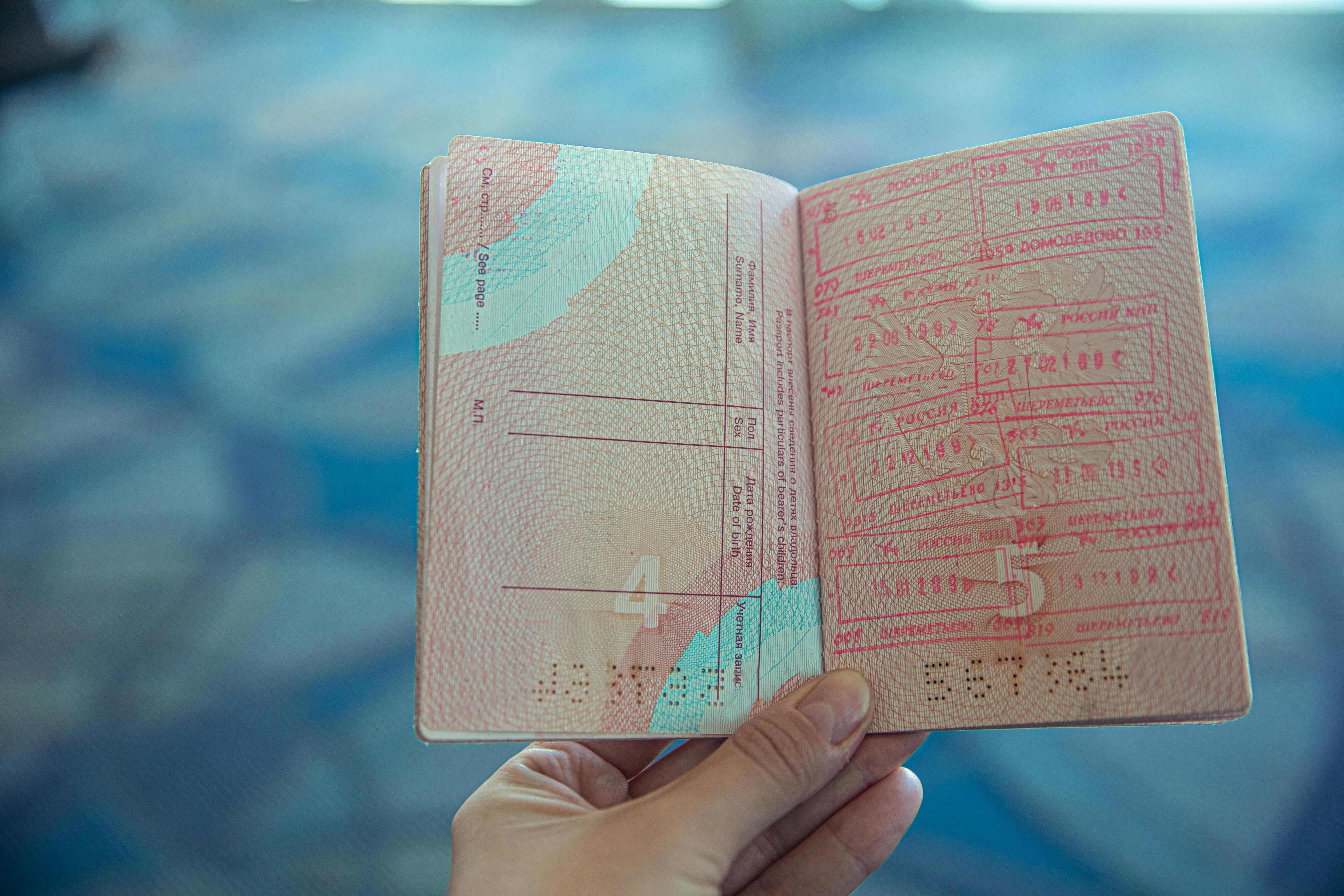 Italy — Close-up view of an open passport displaying various travel stamps in an airport setting.