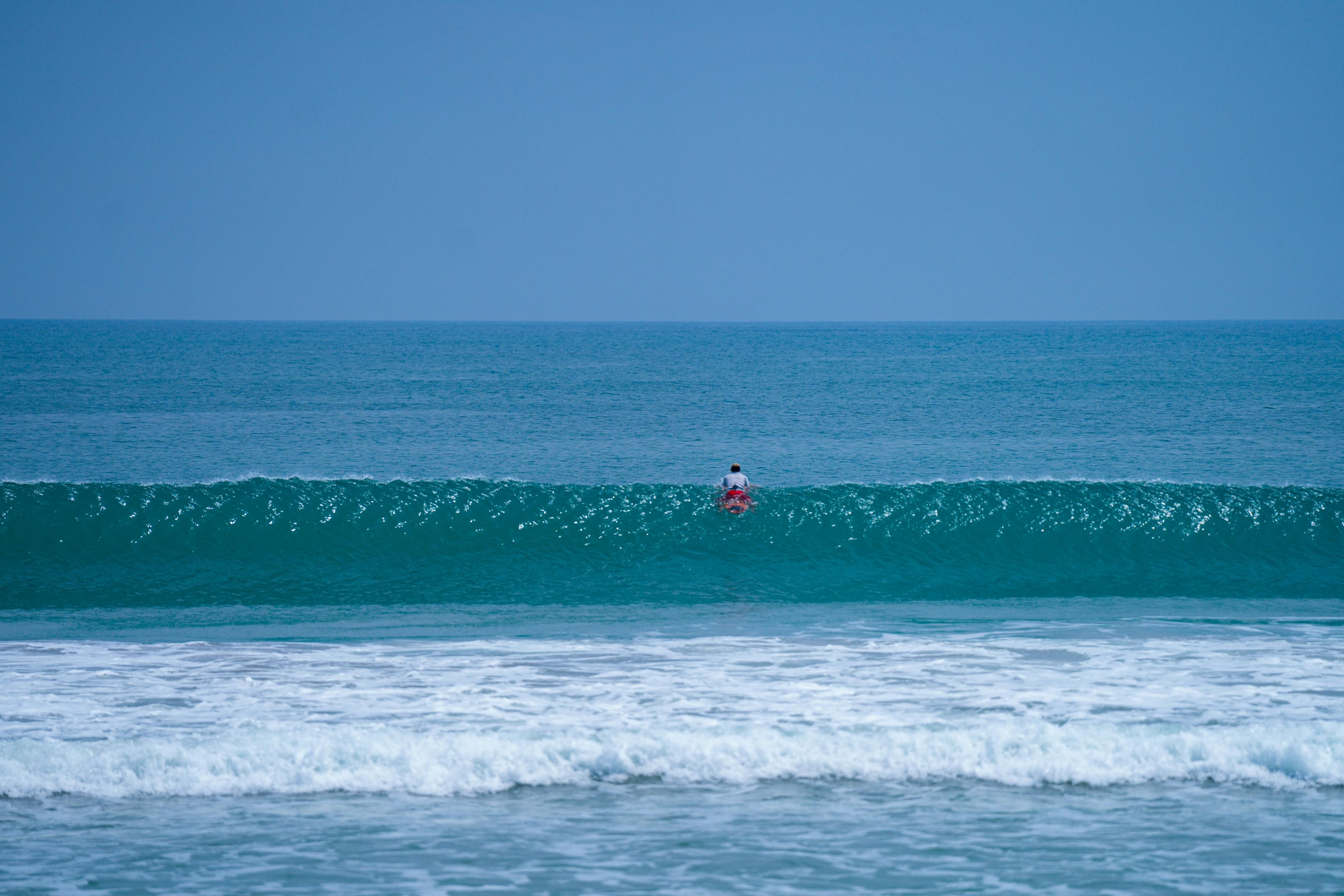 Kuta — A lone surfer paddling through the waves at stunning Kuta Beach, Bali, on a clear day.