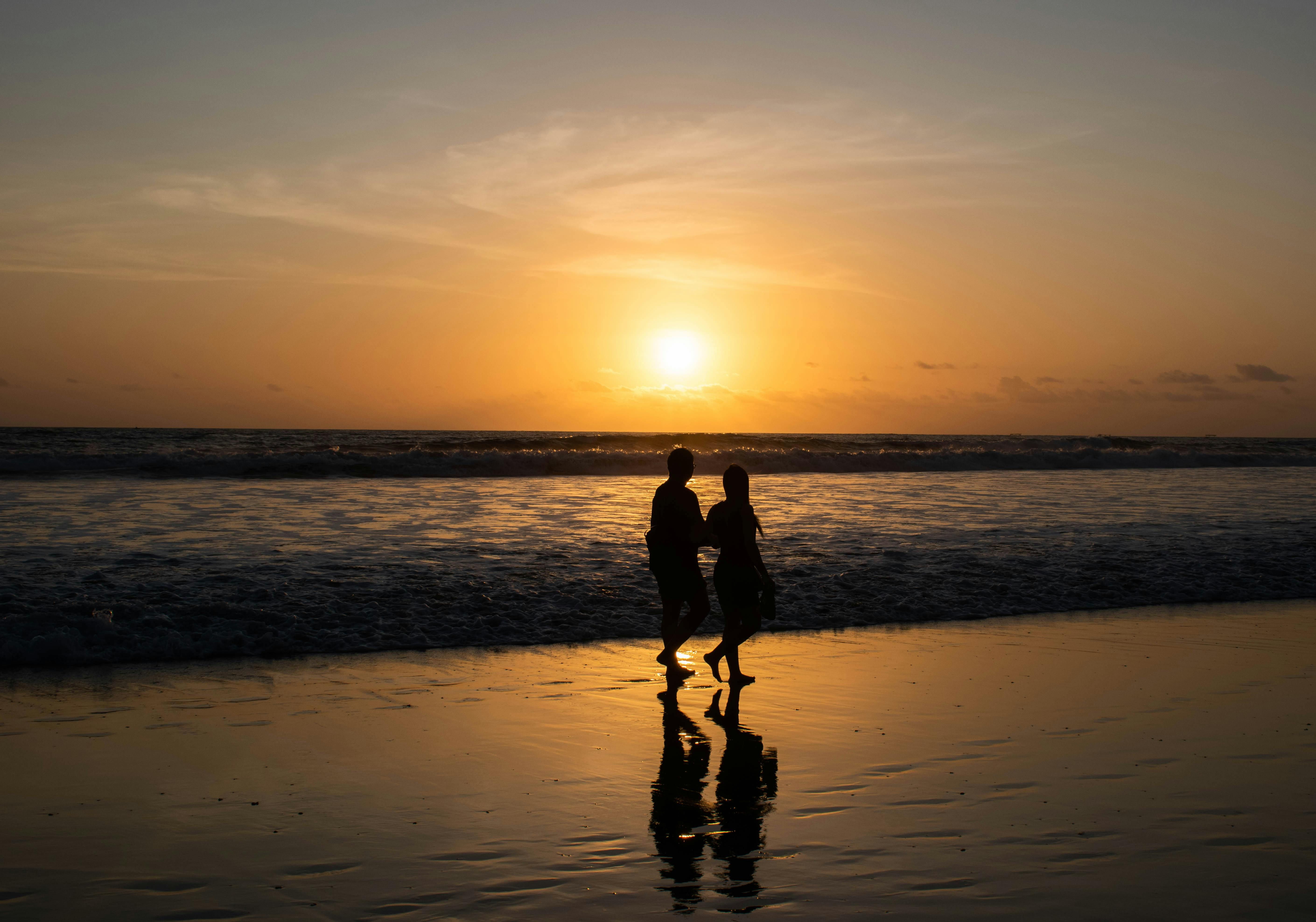 Kuta — Couple enjoying a romantic walk on Kuta Beach, Bali during a stunning sunset.