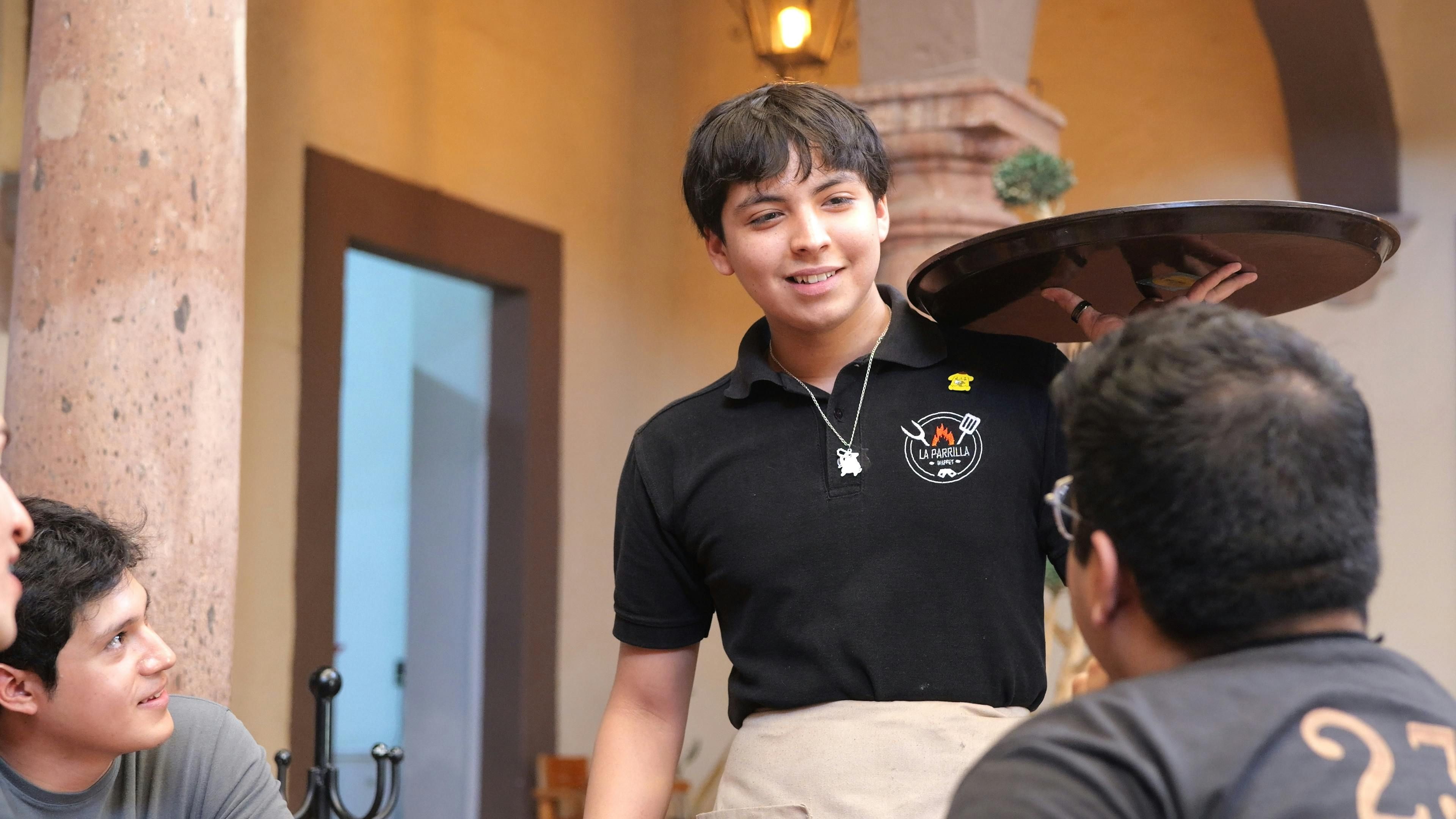 Mexico — A cheerful waiter interacting with customers at a restaurant in Guanajuato, Mexico.