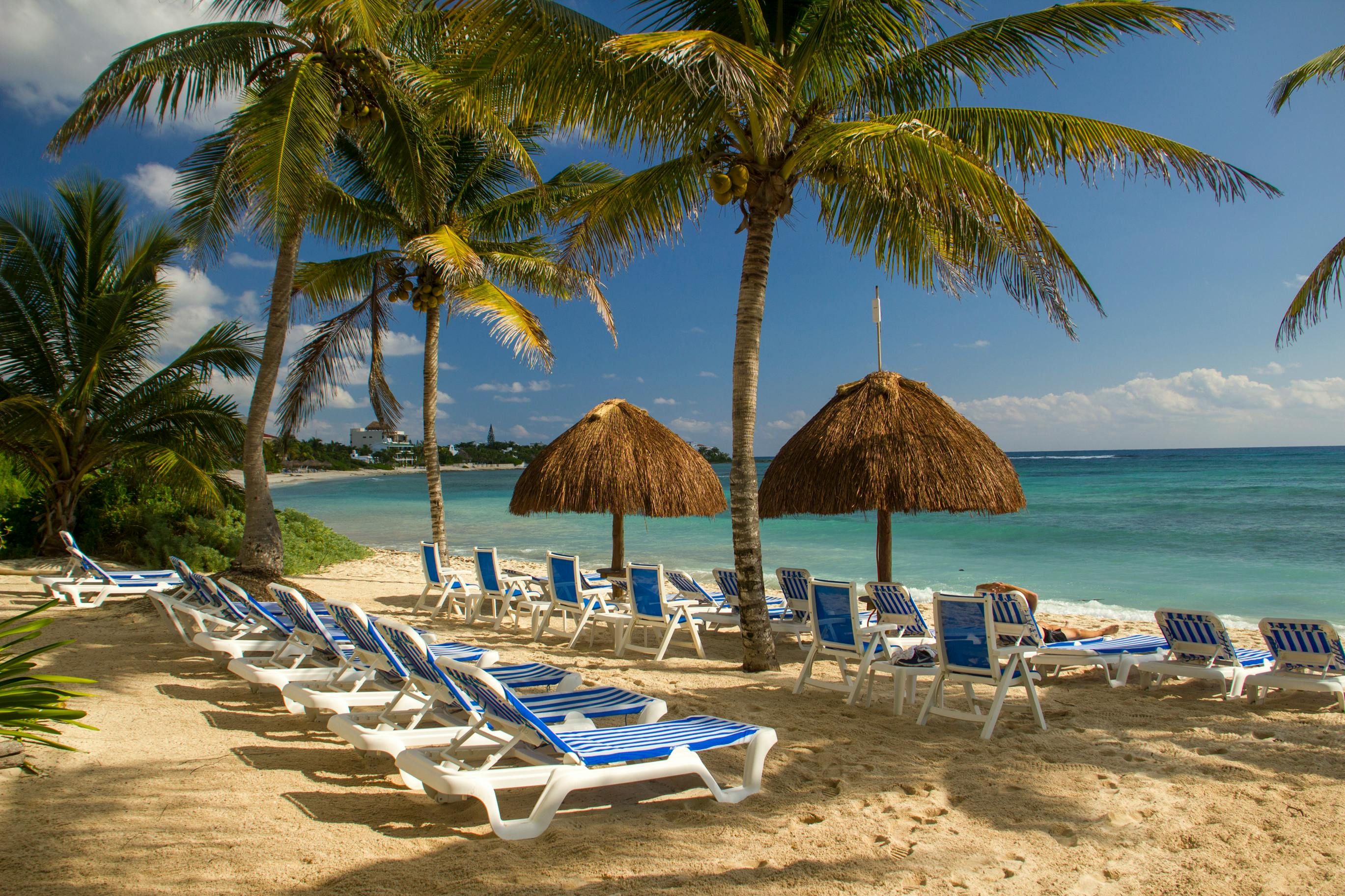 Mexico — Idyllic beach scene in Akumal, Mexico with sun loungers and palm trees.