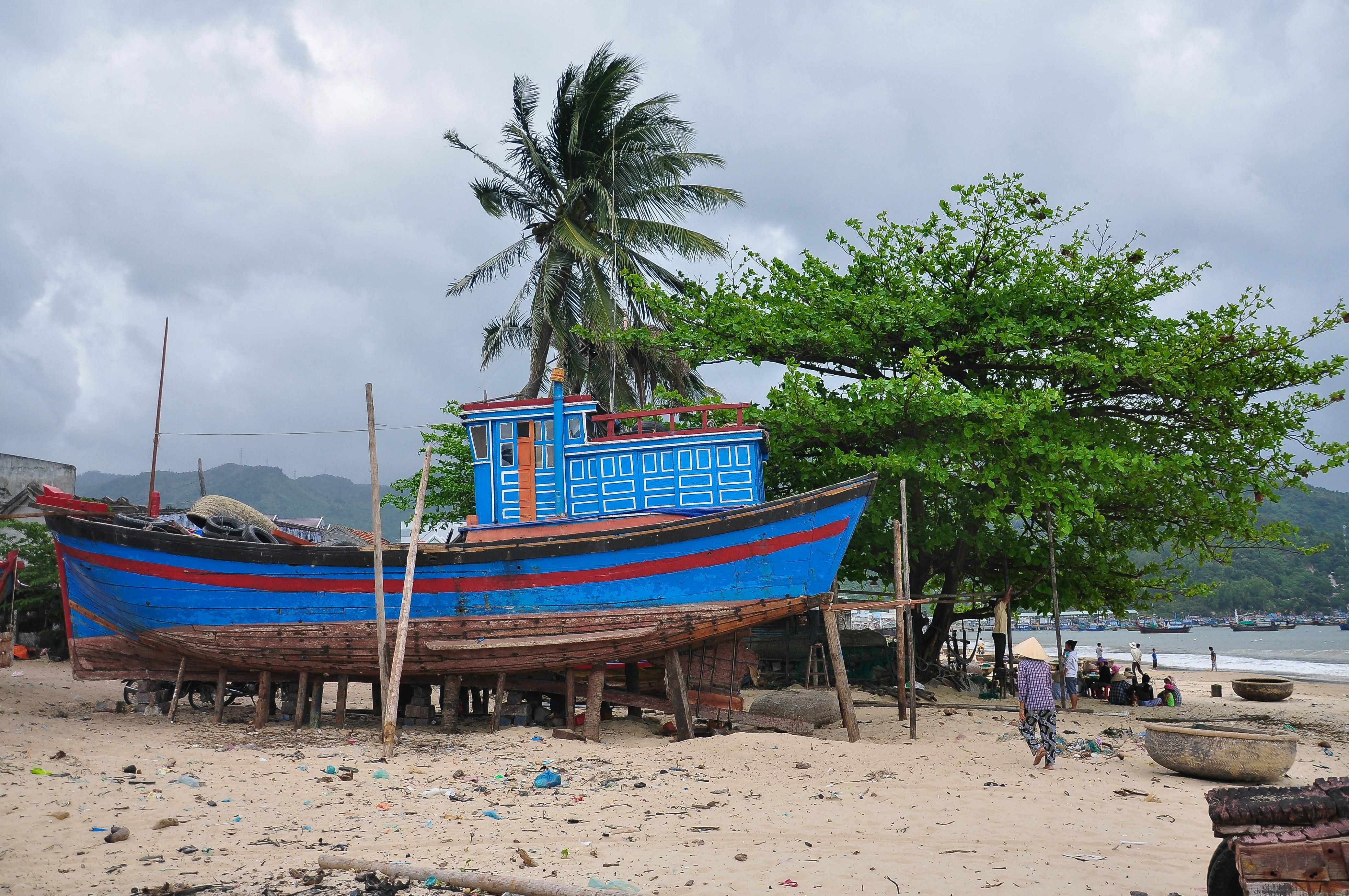 Nha Trang — A vibrant fishing boat stands on a sunny beach in Khánh Hòa, Vietnam, offering a scenic coastal view.