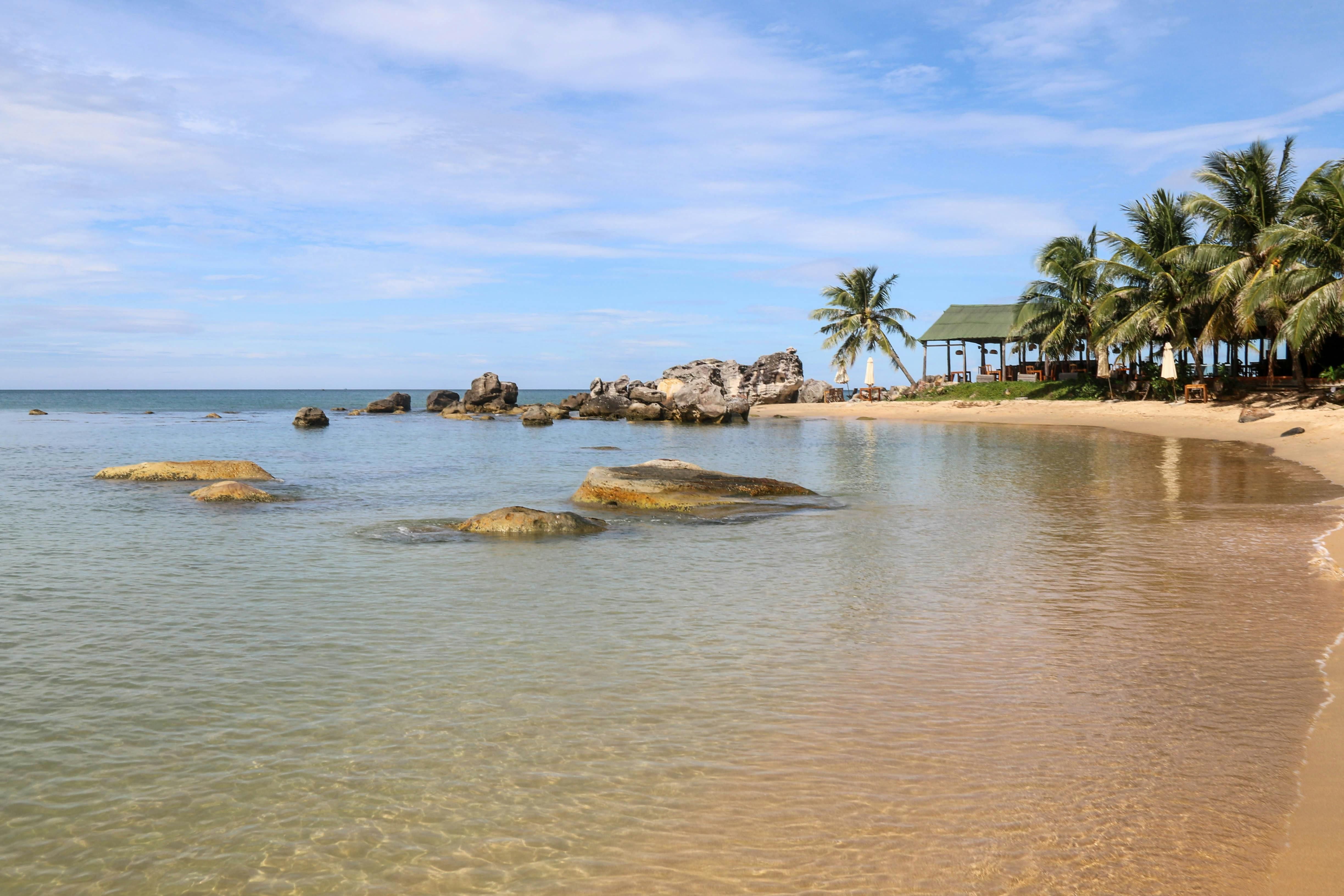 Phu Quoc — Serene beach landscape with palm trees, rocks, and clear water. Perfect tropical getaway setting.