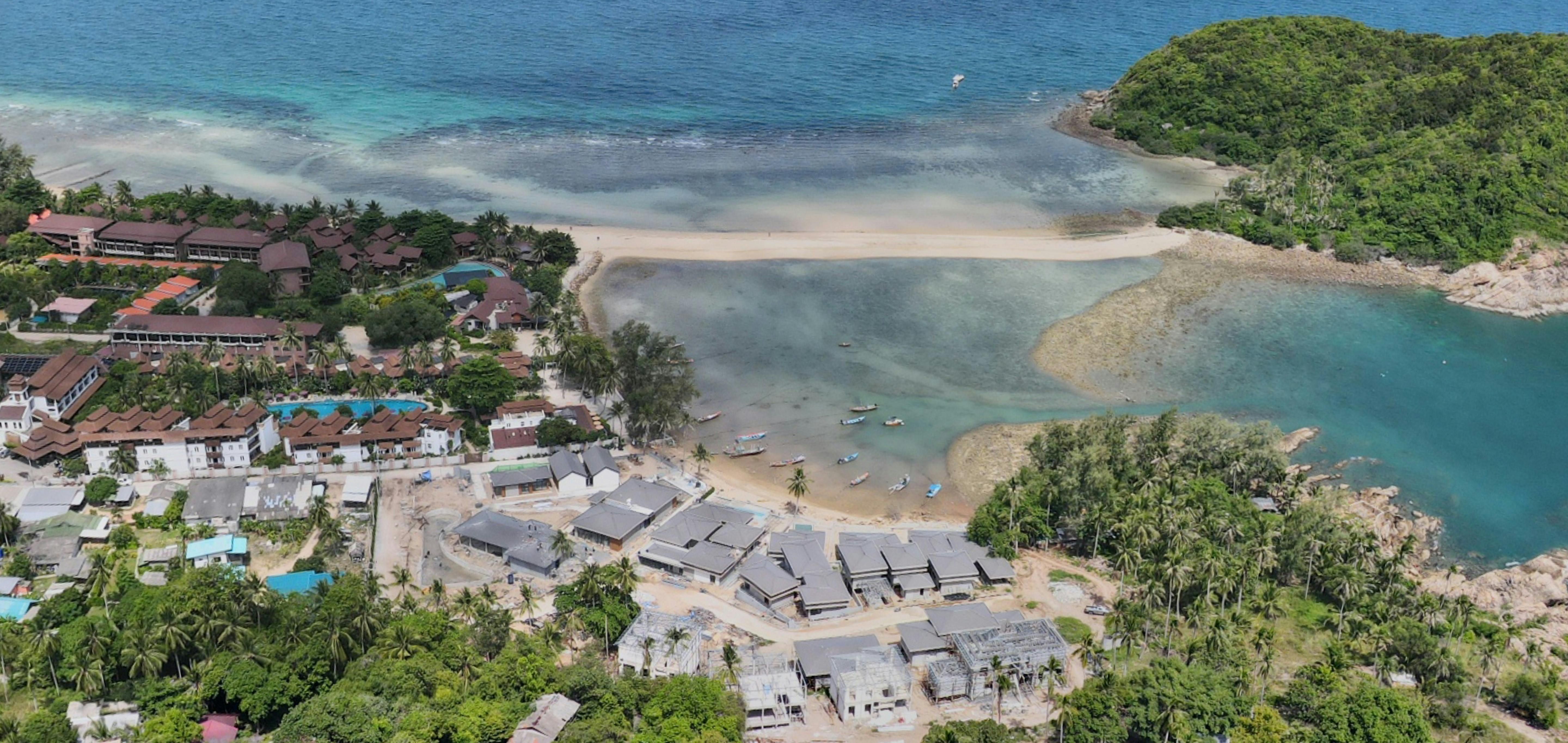 Thailand — Stunning aerial view of a coastal town featuring a sandy beach, lush greenery, and clear blue waters.