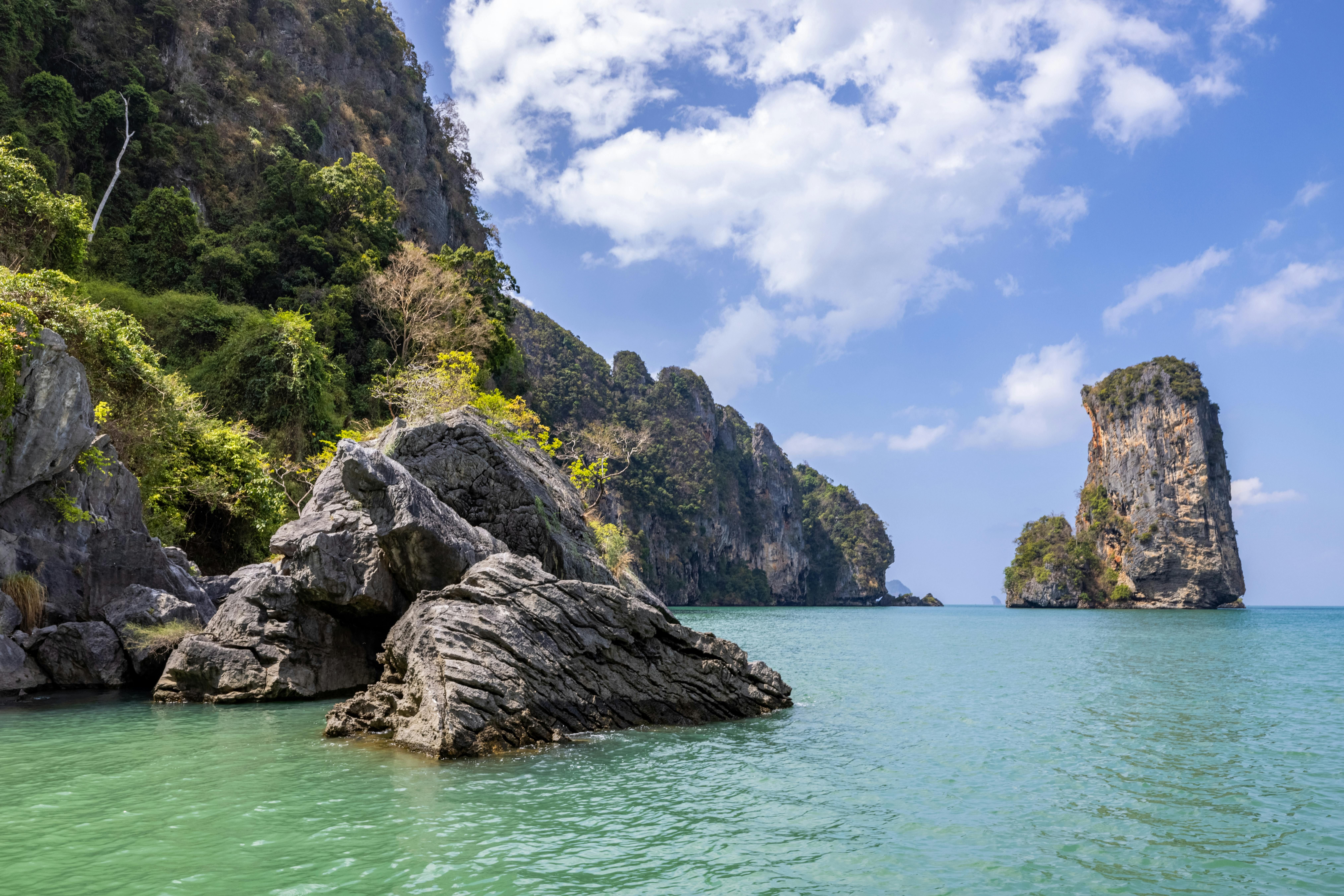 Thailand — Explore the serene beauty of Ao Nang Beach with towering cliffs and clear waters.