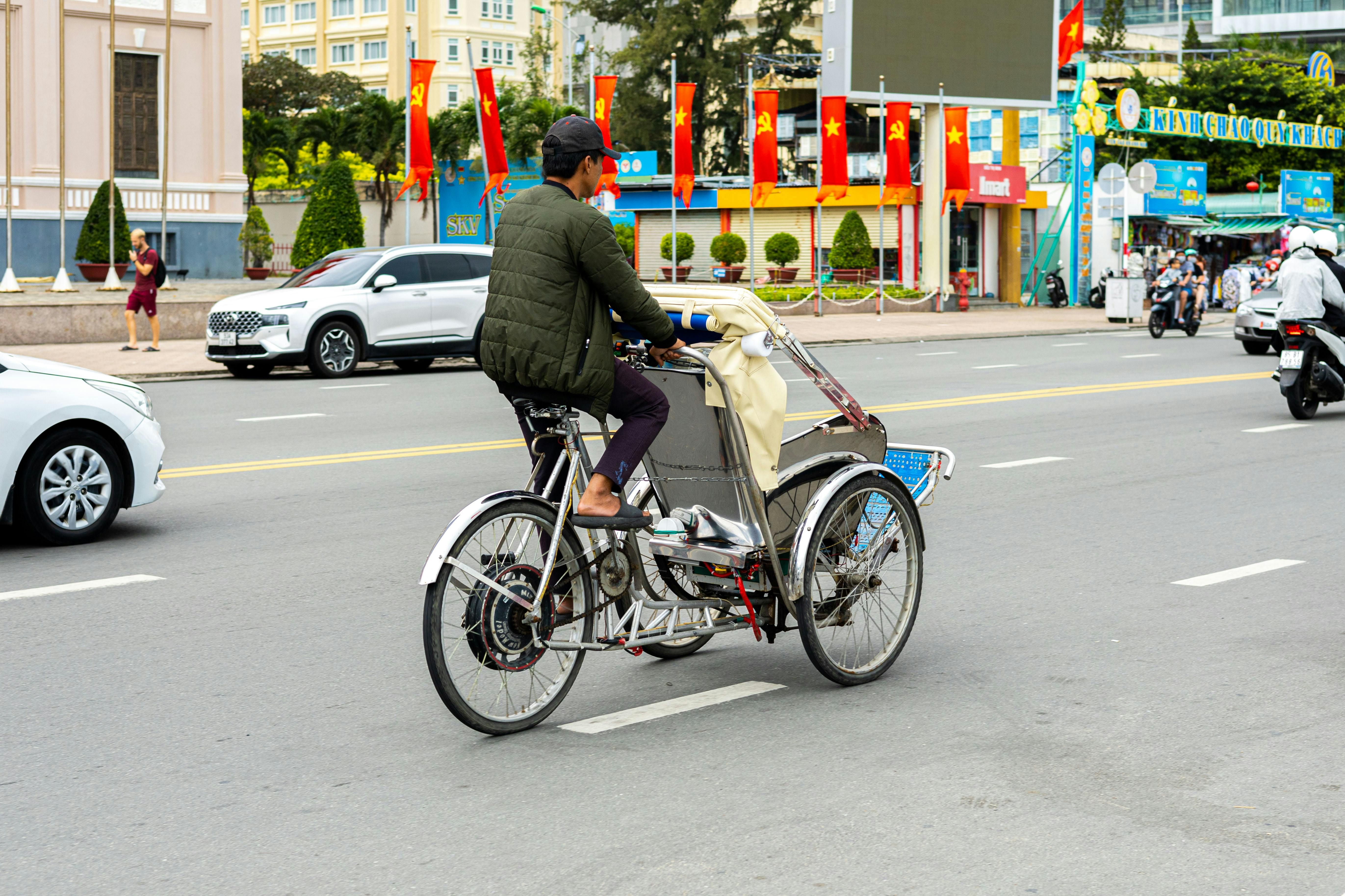 Vietnam — A man rides a cyclo on a busy street in Nha Trang, Vietnam, surrounded by traffic.