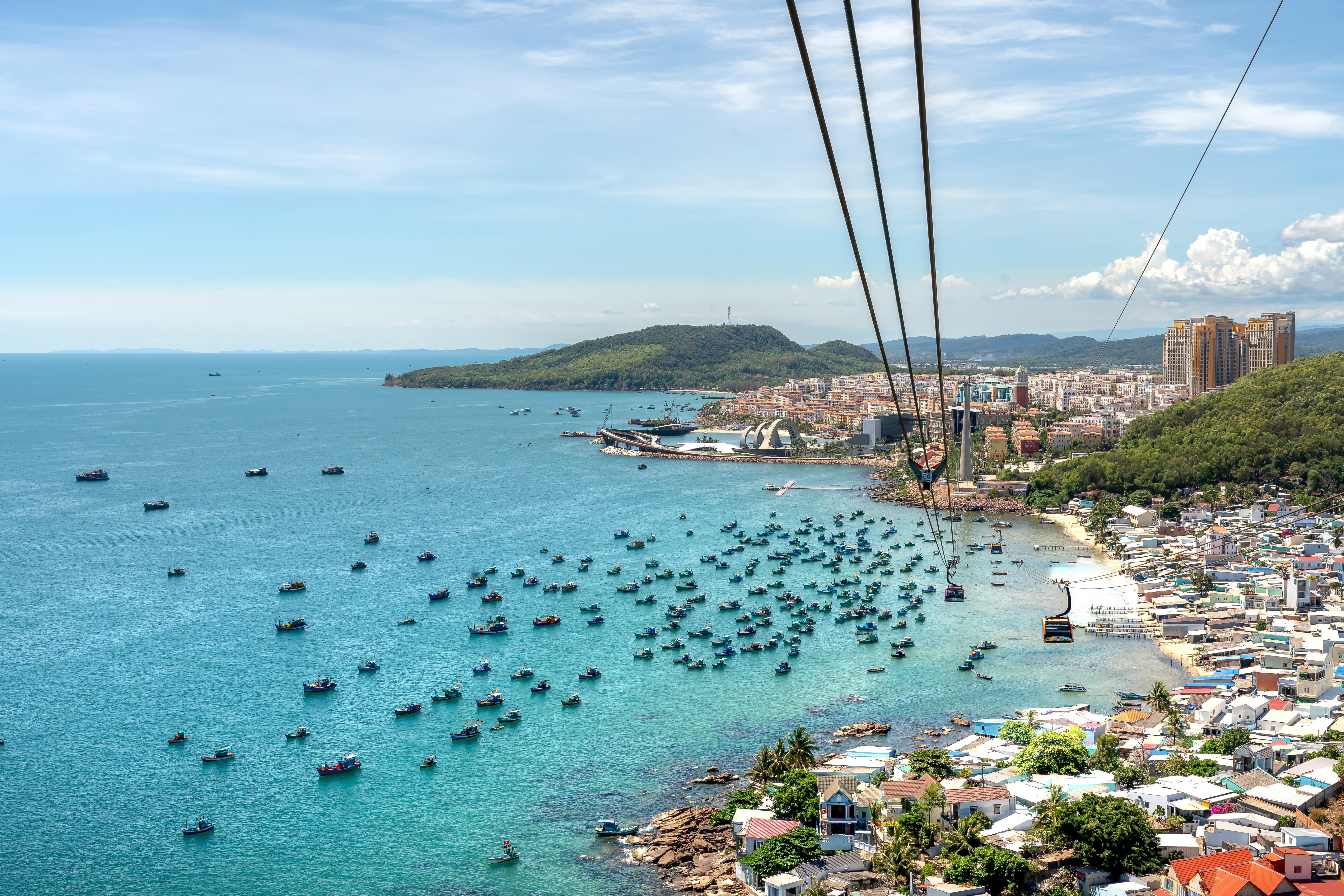 Vietnam — A breathtaking aerial view of Phu Quoc Island with boats, coastline, and cable car over blue water.