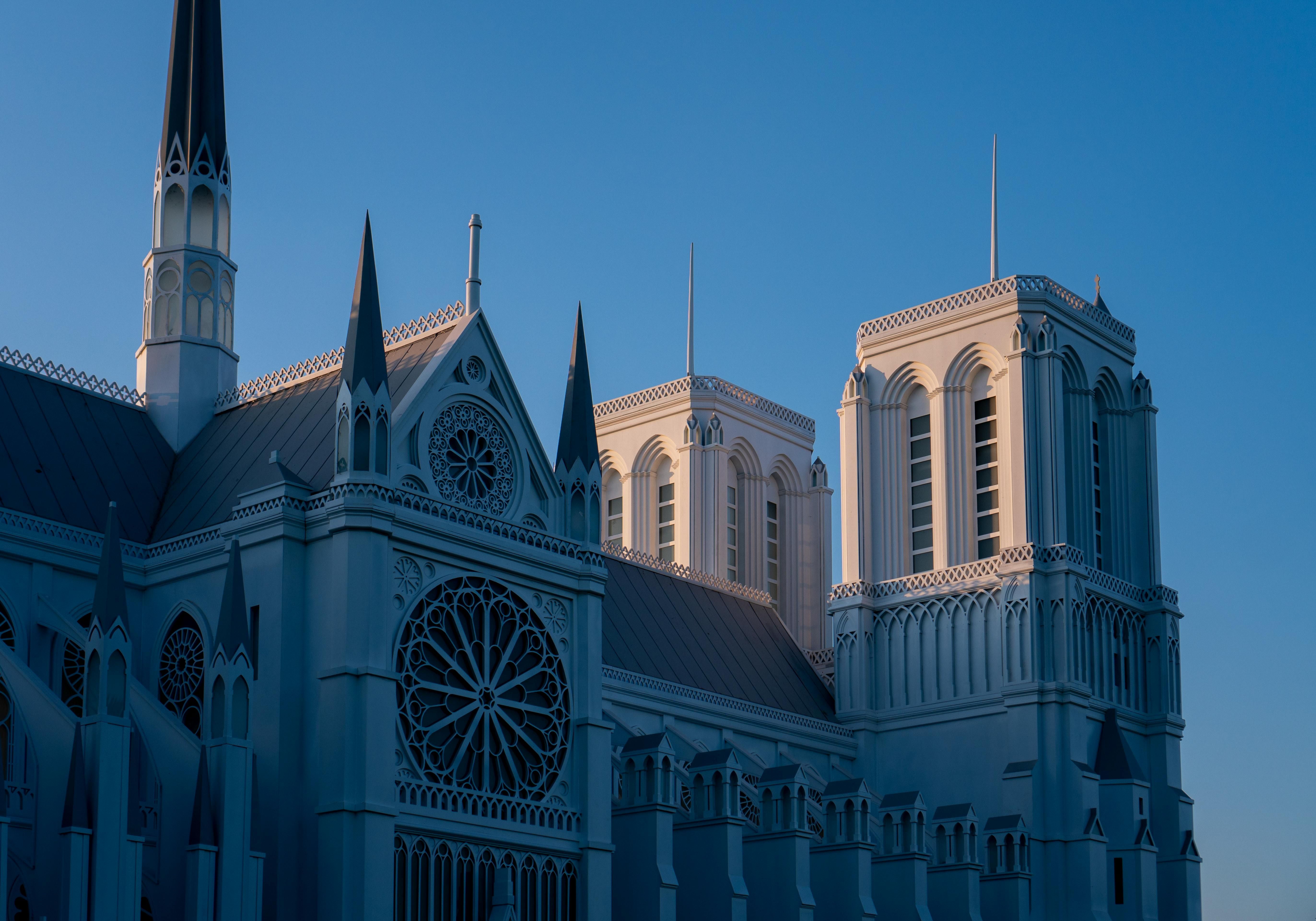 Vietnam — An elegant Gothic cathedral with intricate spires illuminated by sunset light against a clear sky.
