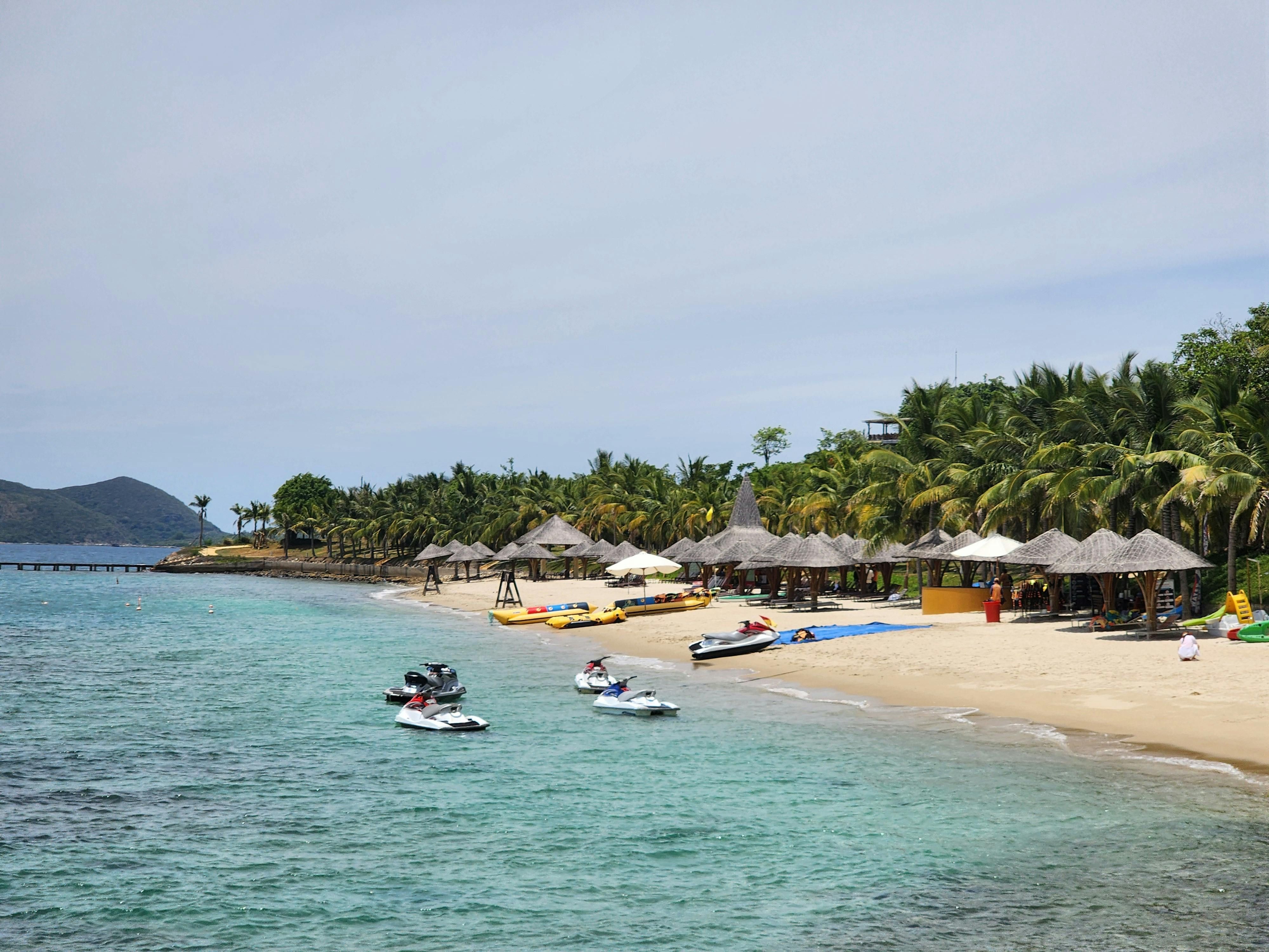 Vietnam — A serene tropical beach with jet skis, palm trees, and thatched umbrellas along the shoreline.